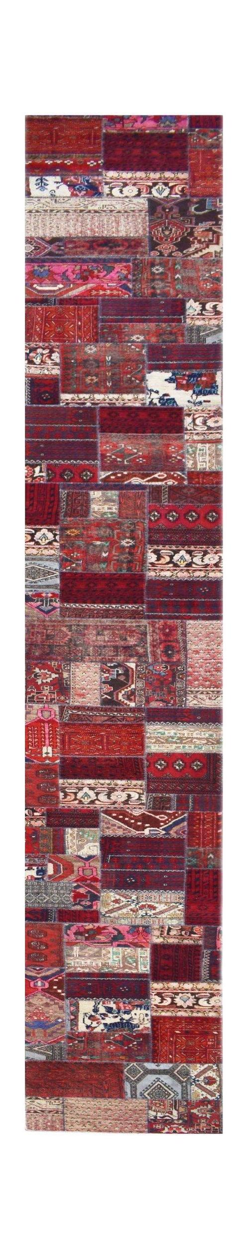 A handmade wool runner rug featuring a vintage patchwork design in various shades of red.