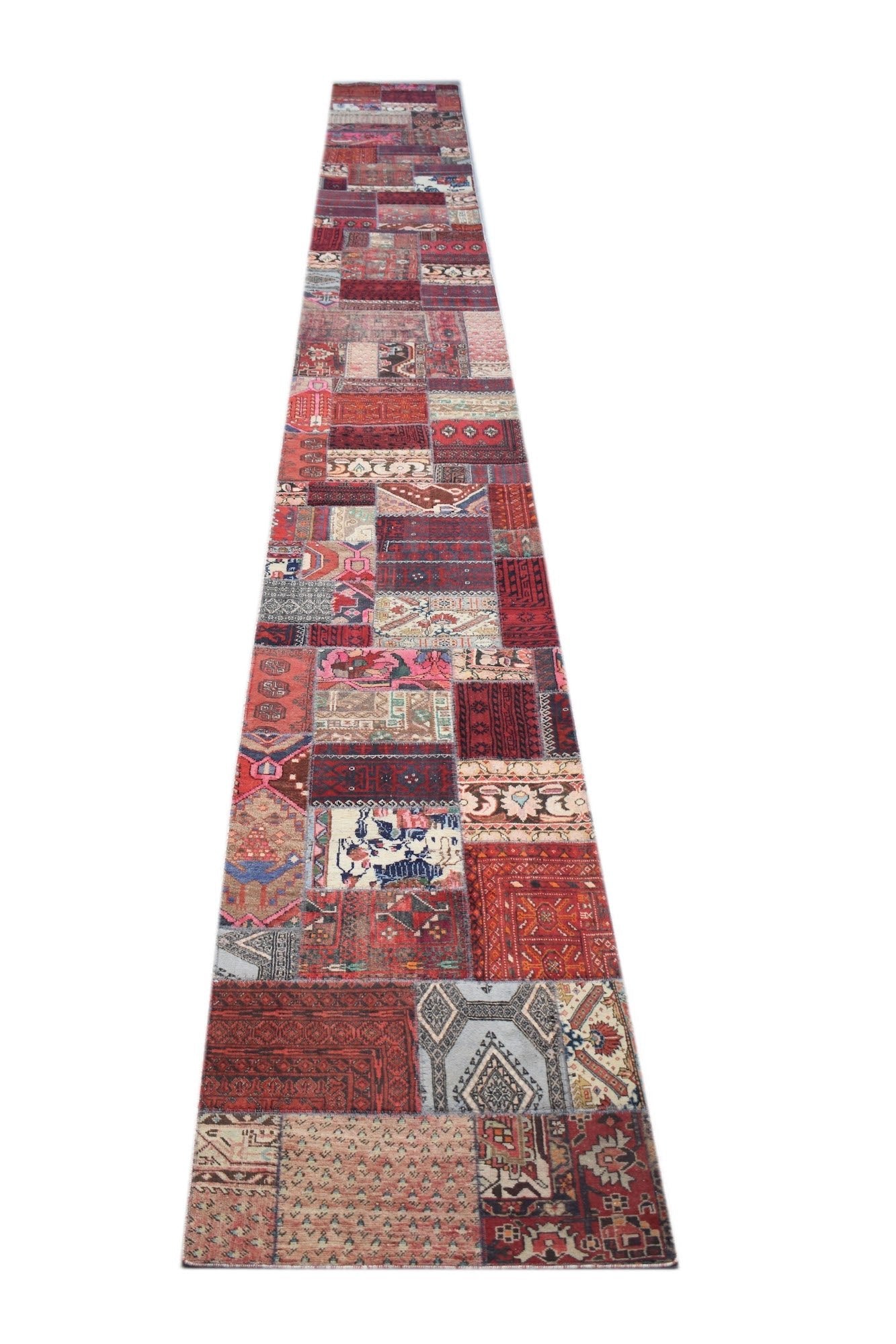 A long, handmade vintage patchwork runner rug featuring a variety of colorful wool patterns.