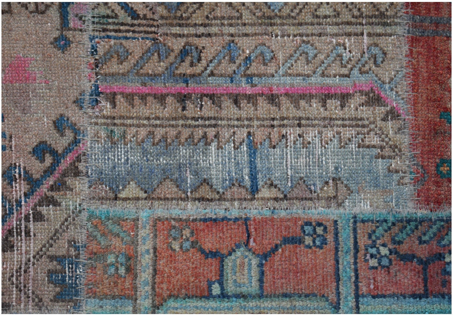 A handmade vintage patchwork runner featuring a variety of colorful wool rug fragments.