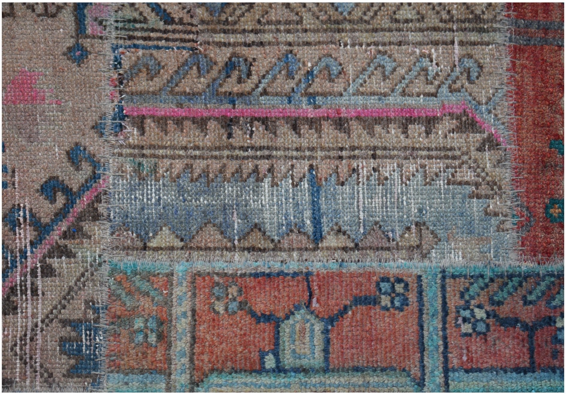 A handmade vintage patchwork runner featuring a variety of colorful wool rug fragments.