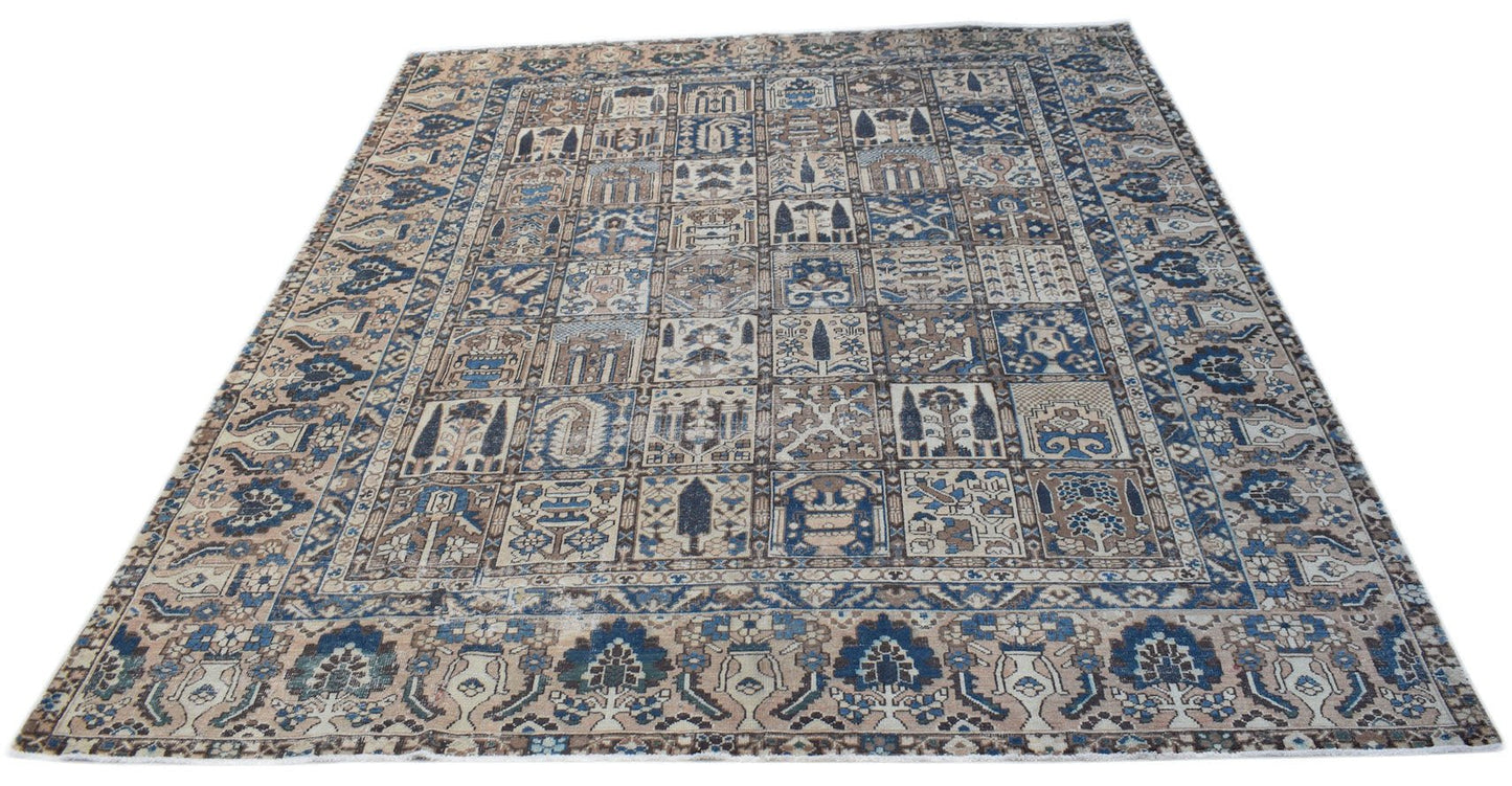 A handmade vintage Persian Bakhtiari rug featuring a blue and beige grid of floral garden motifs.