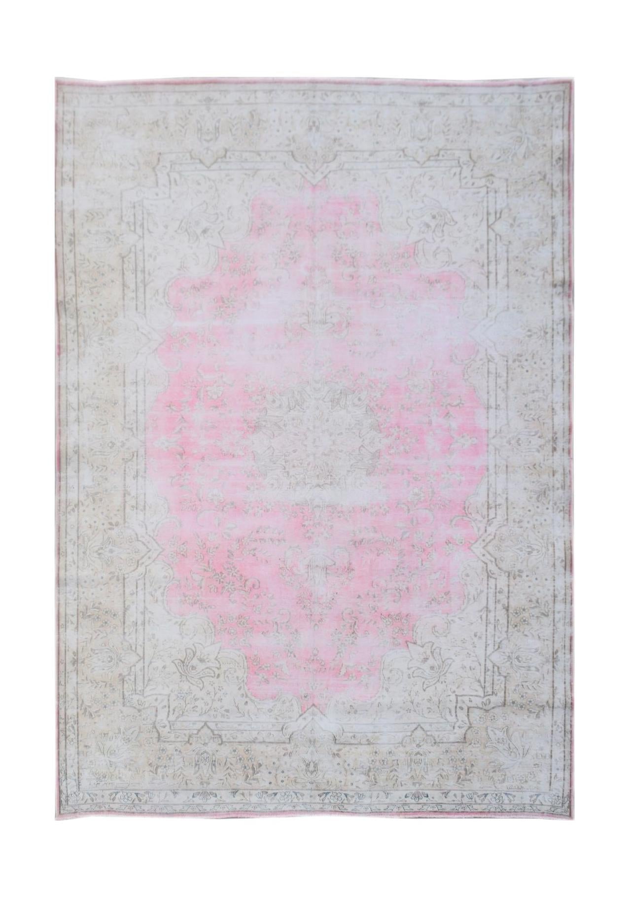 A vintage Persian Kerman rug featuring a central pink medallion on a light floral background.