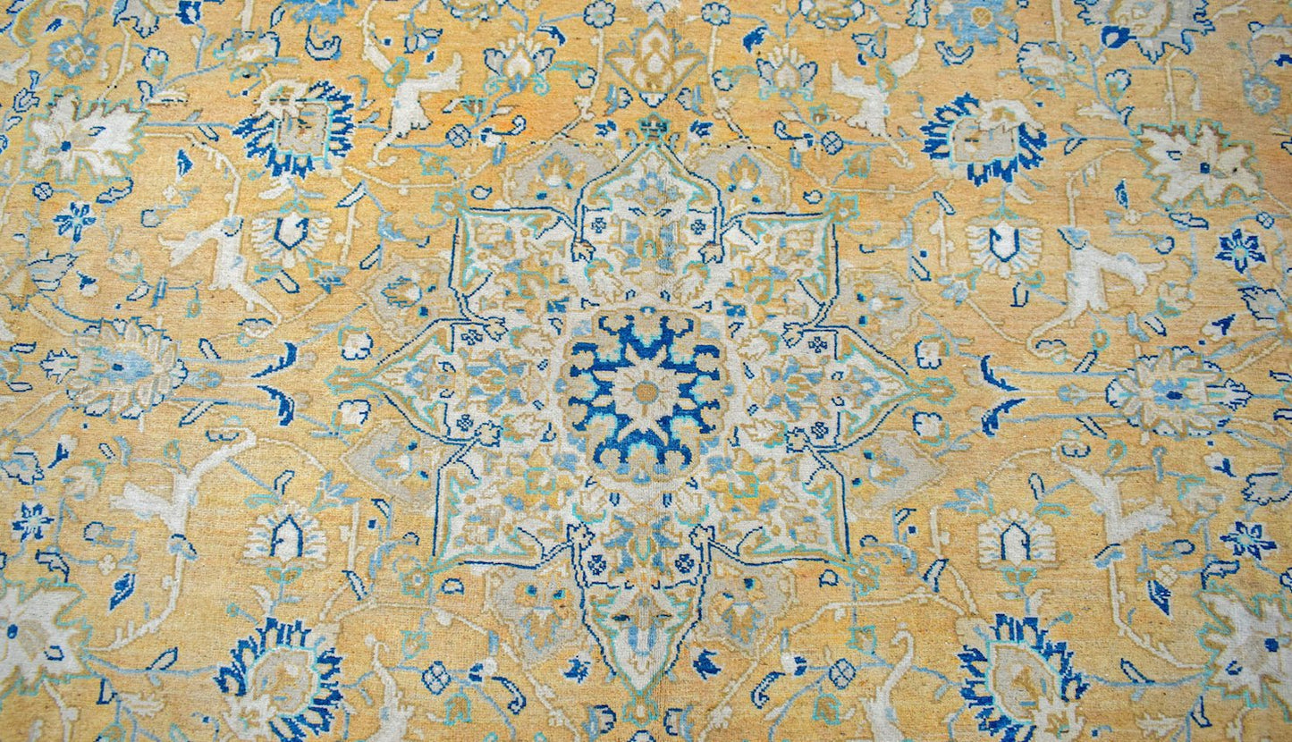 A vintage Persian Kashan rug featuring an intricate floral medallion in blue and cream on gold.