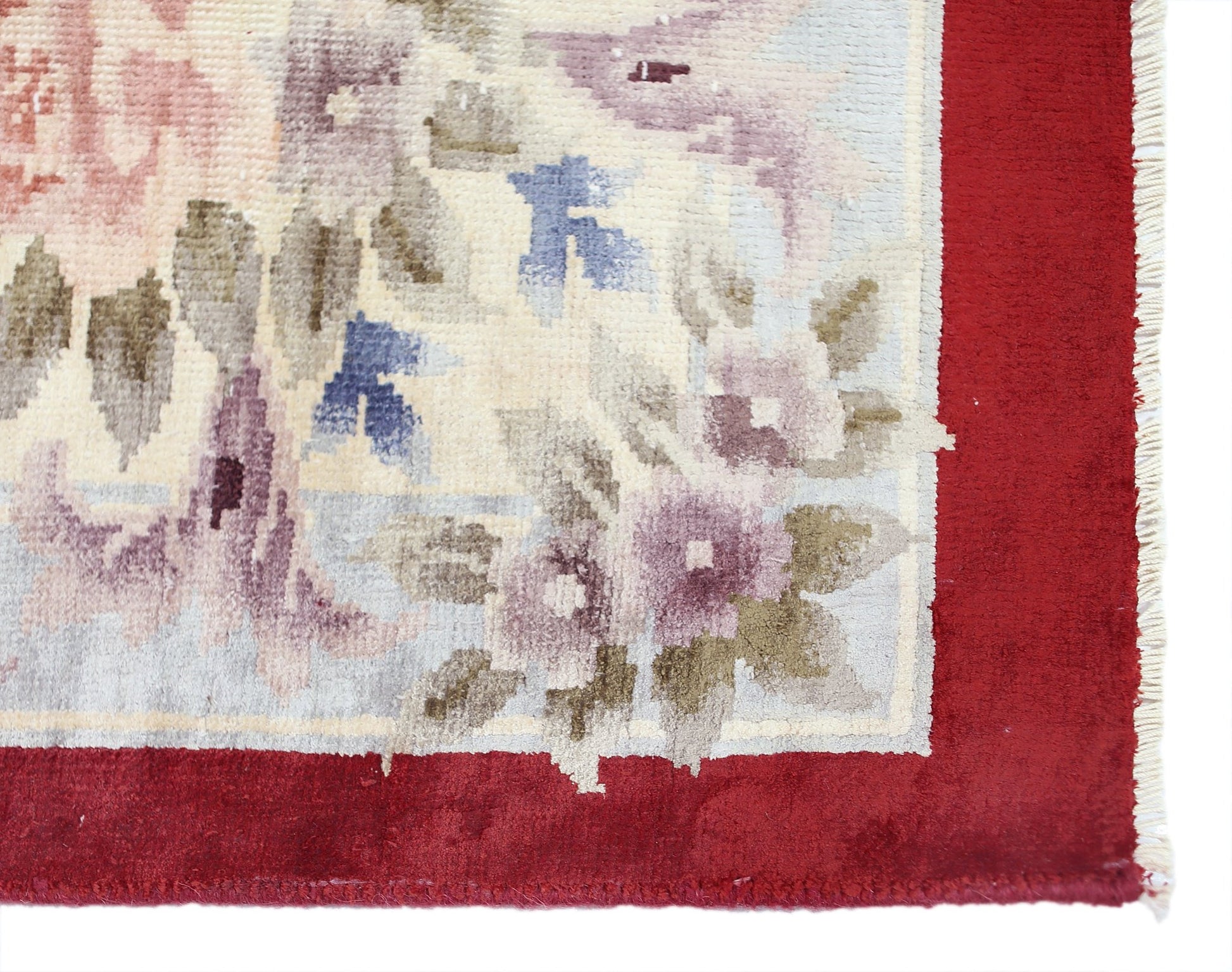 A vintage Chinese silk rug featuring a floral pattern with a red border and fringe.