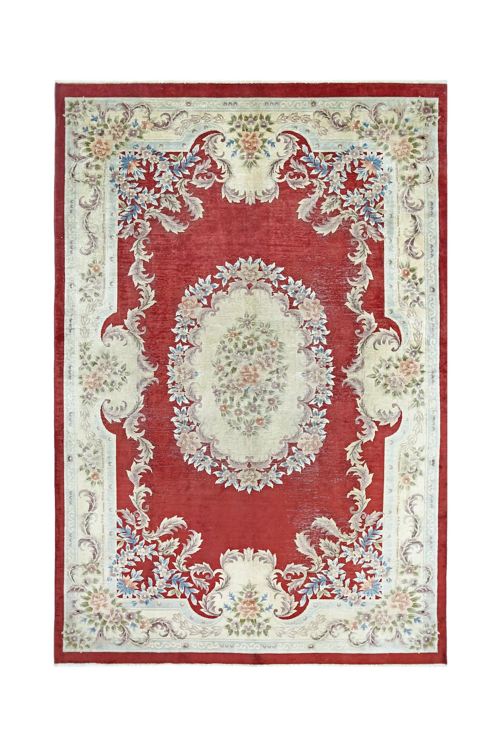 A vintage Chinese silk rug featuring a central floral medallion on a red field with ornate borders.
