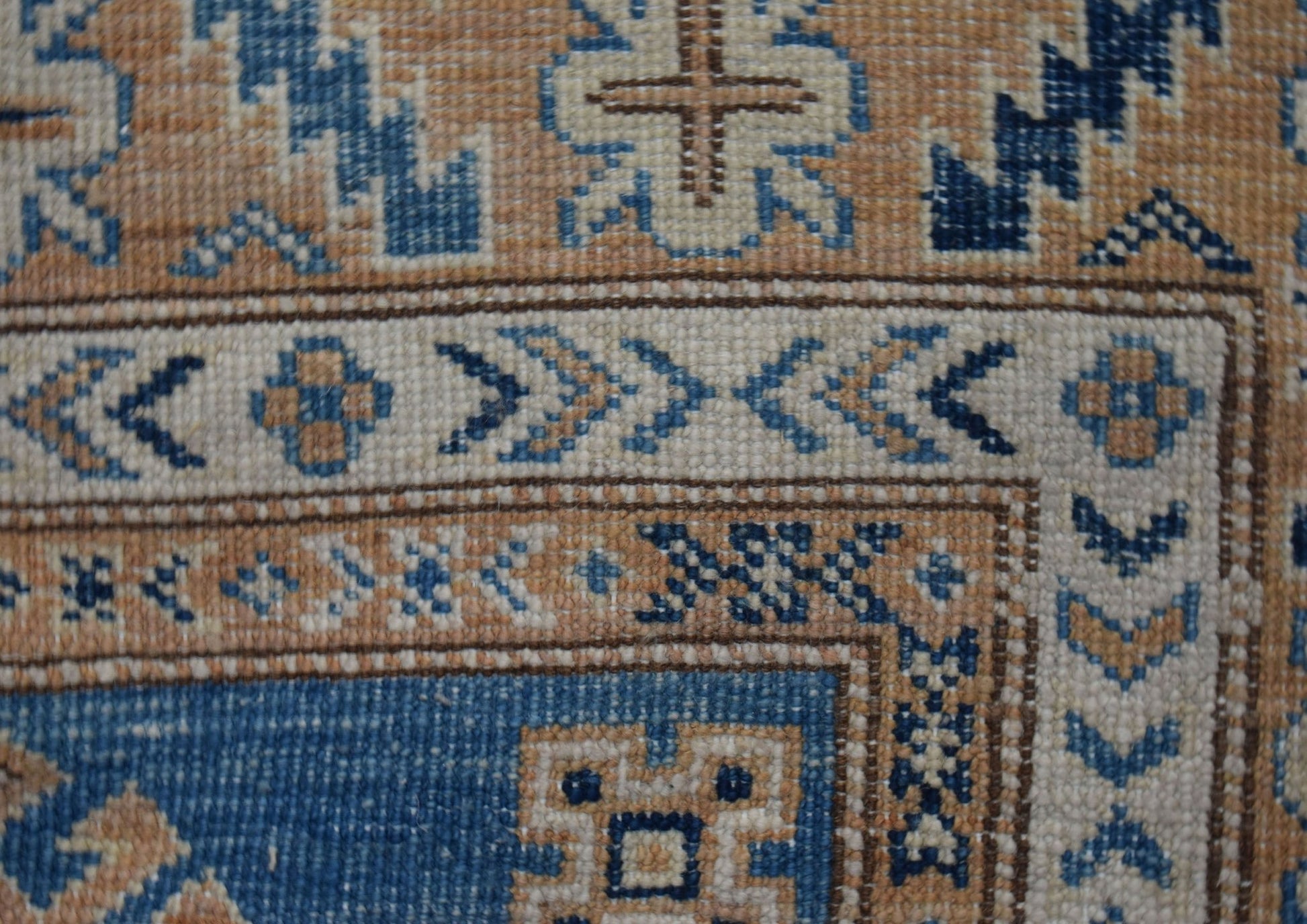 A close-up of an Afghan Super Kazakh runner featuring intricate geometric patterns in blue and tan.