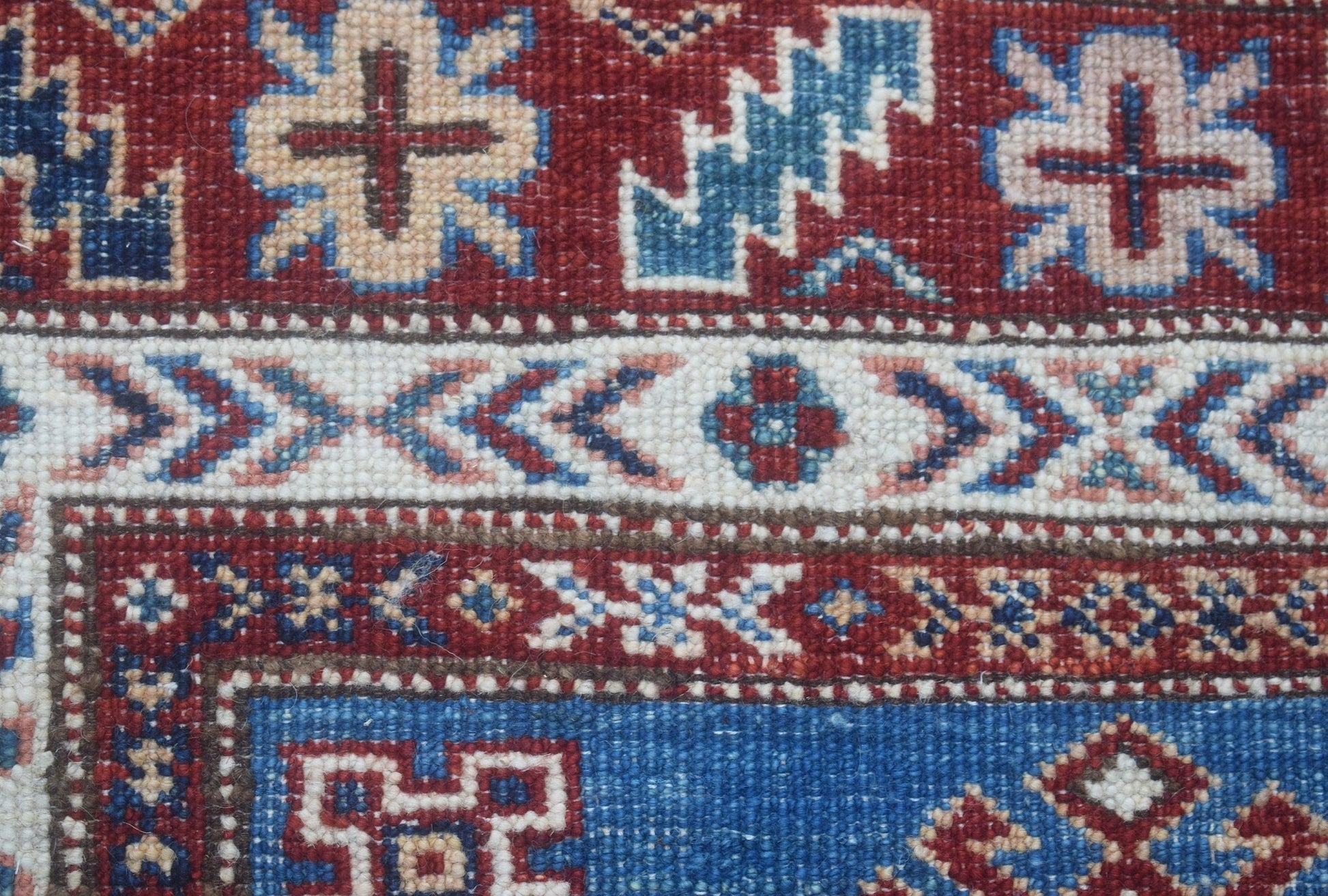 A close-up of an Afghan Super Kazakh runner featuring intricate geometric patterns in red and blue.