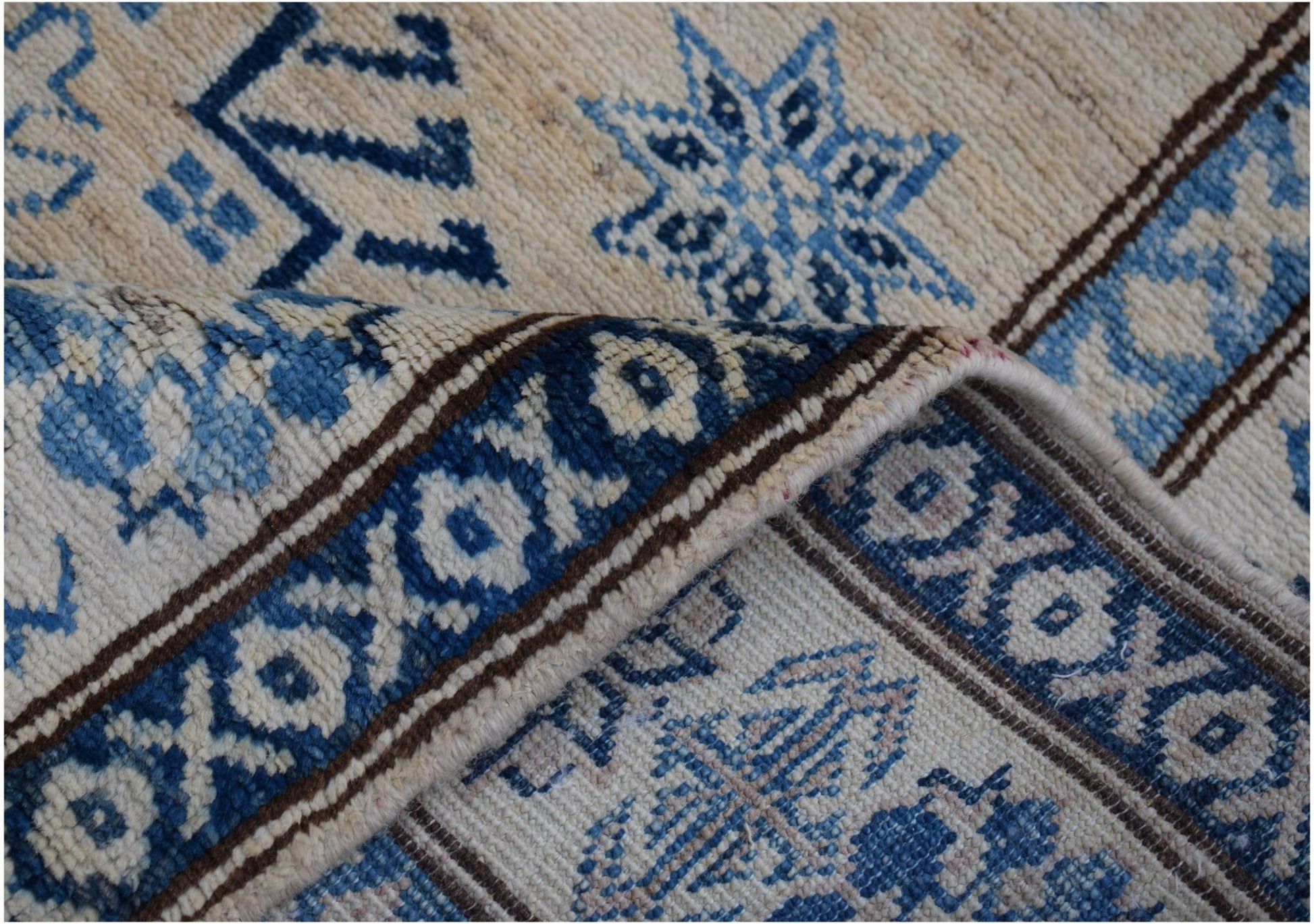 A handmade Afghan Super Kazakh runner featuring a beige background with blue geometric patterns.