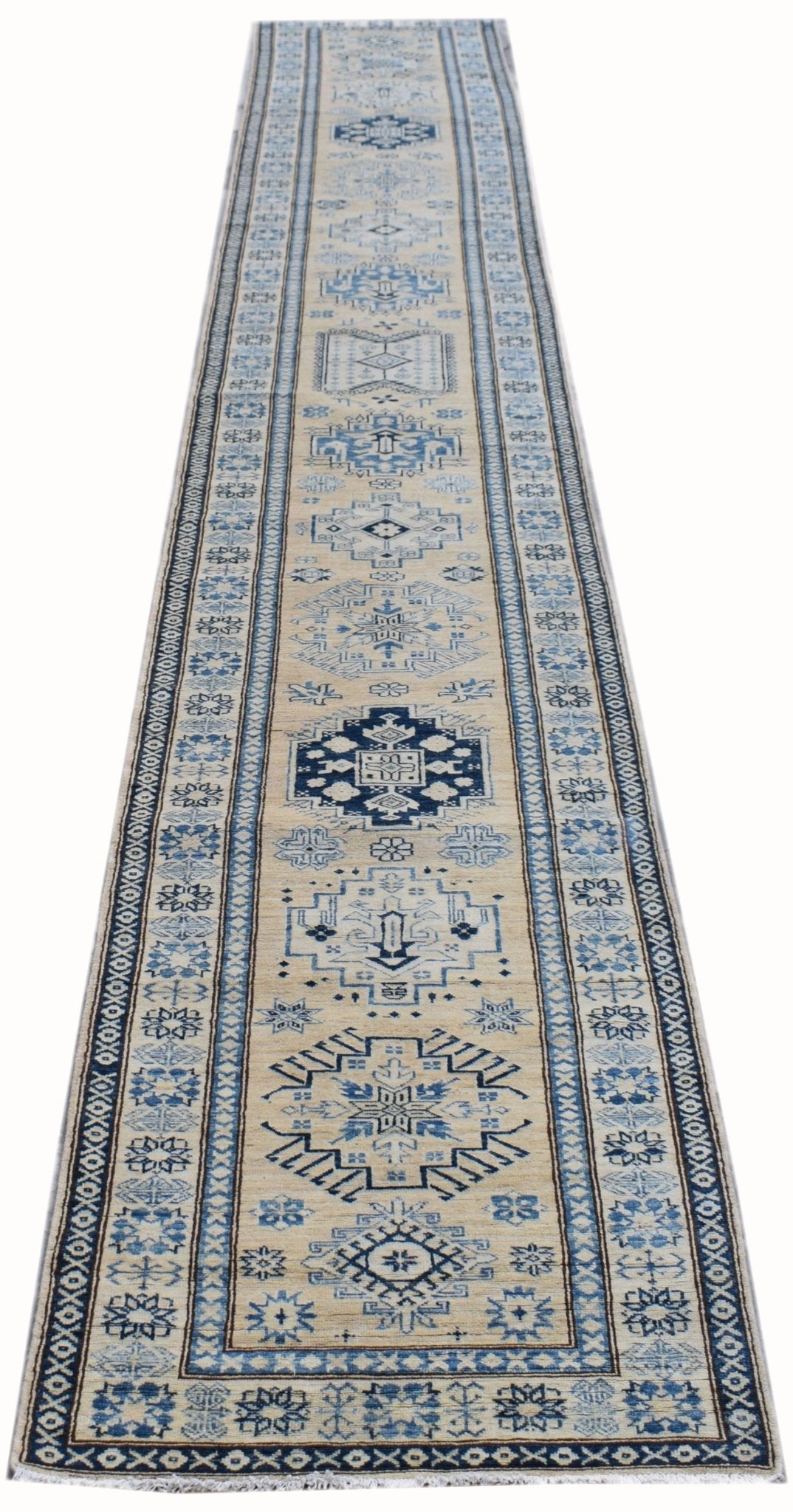 Handmade Afghan Super Kazakh runner rug featuring blue geometric patterns on a beige wool field.