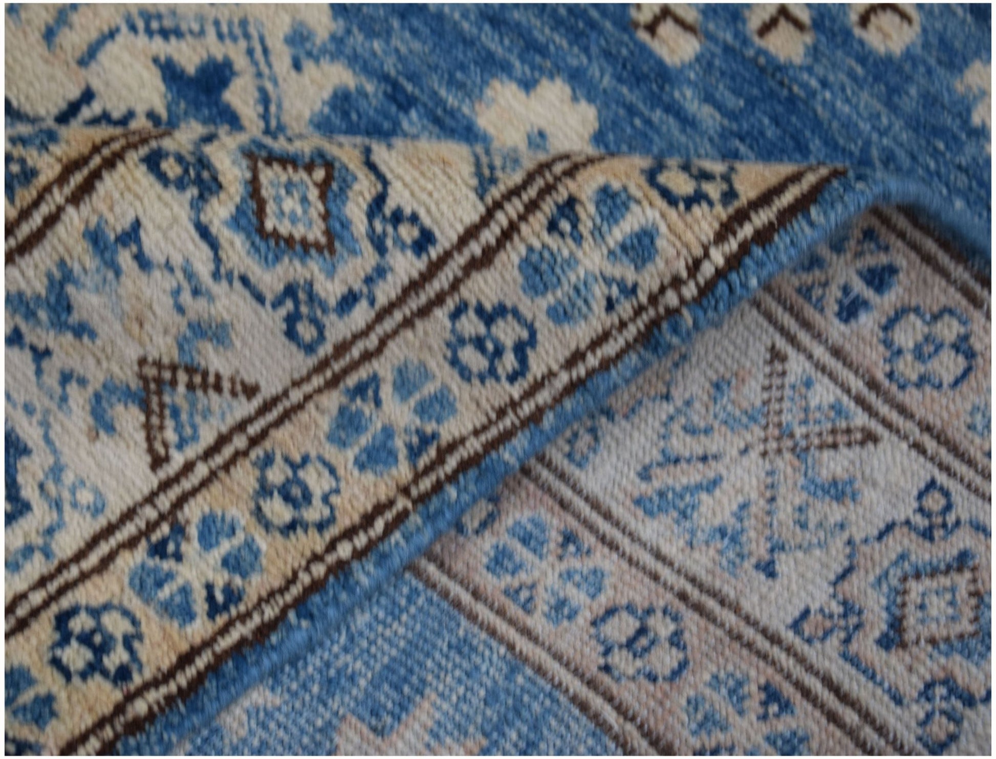 A handmade Afghan Super Kazakh runner featuring a blue and beige floral geometric pattern.