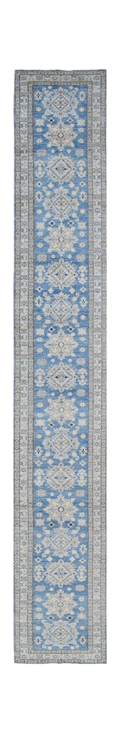 A long, handmade Afghan runner rug featuring a blue field with repeating beige floral medallions.