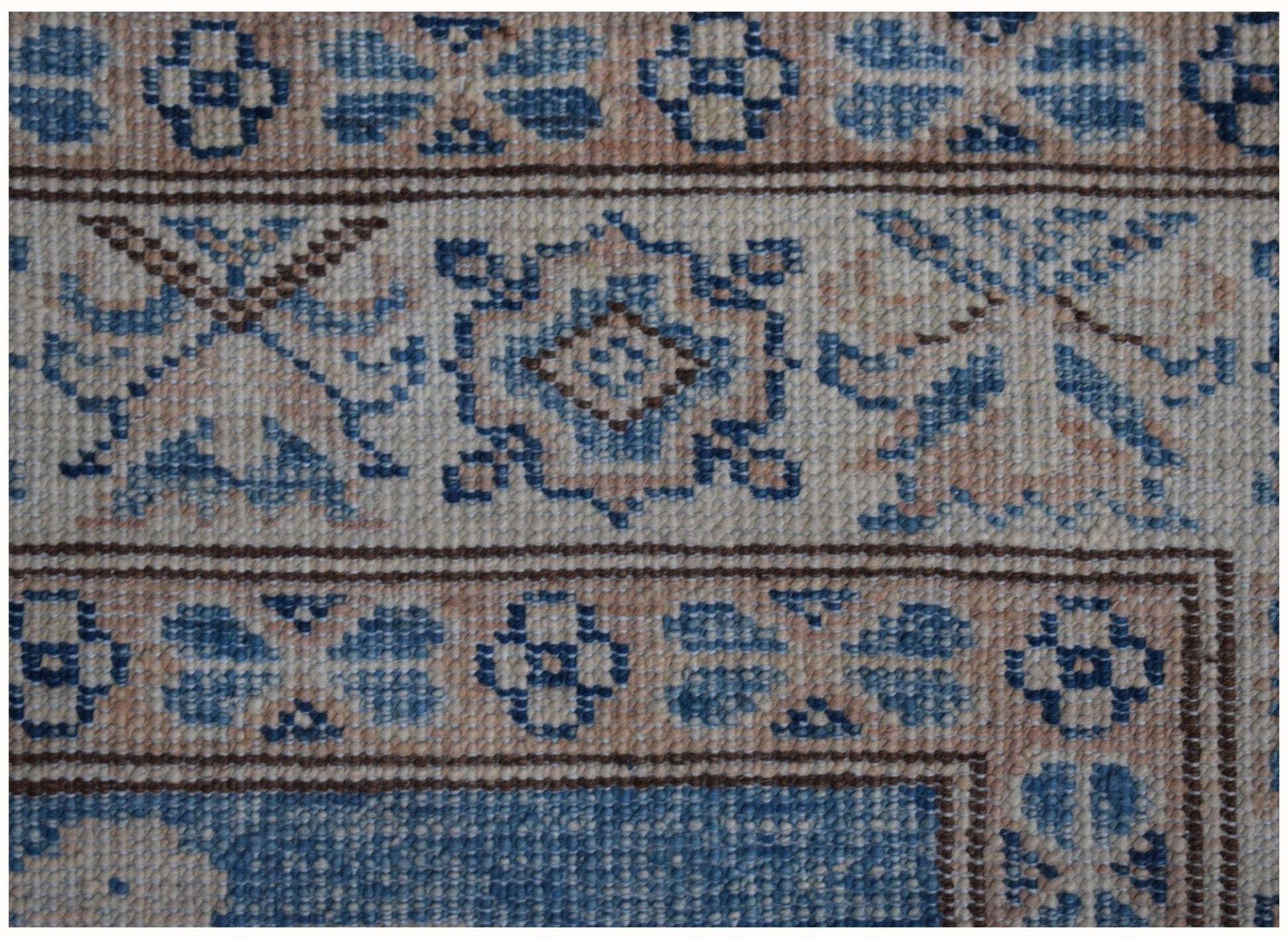 A close-up of an Afghan Super Kazakh runner rug featuring geometric floral patterns in blue and beige.