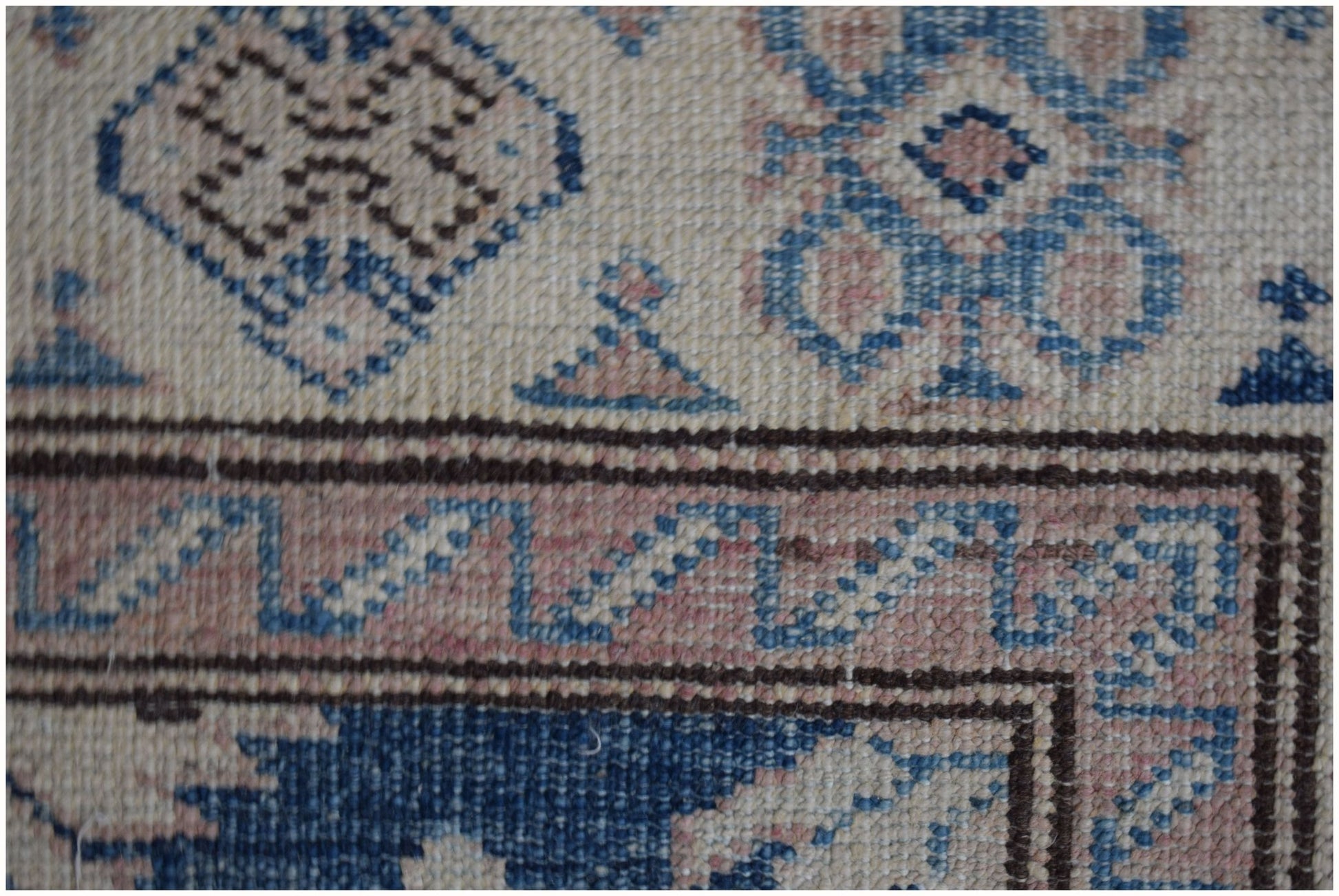 A close-up of an Afghan Super Kazakh runner featuring geometric patterns in blue, beige, and pink.