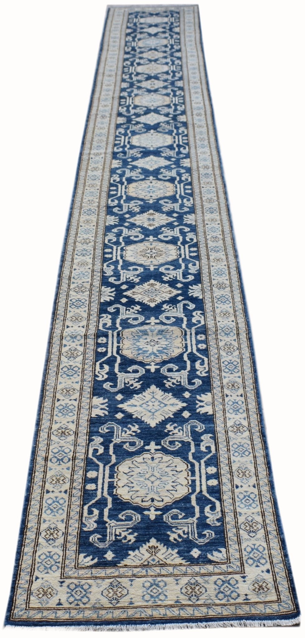 A long, handmade Afghan Super Kazakh runner rug featuring a blue field with beige geometric motifs.