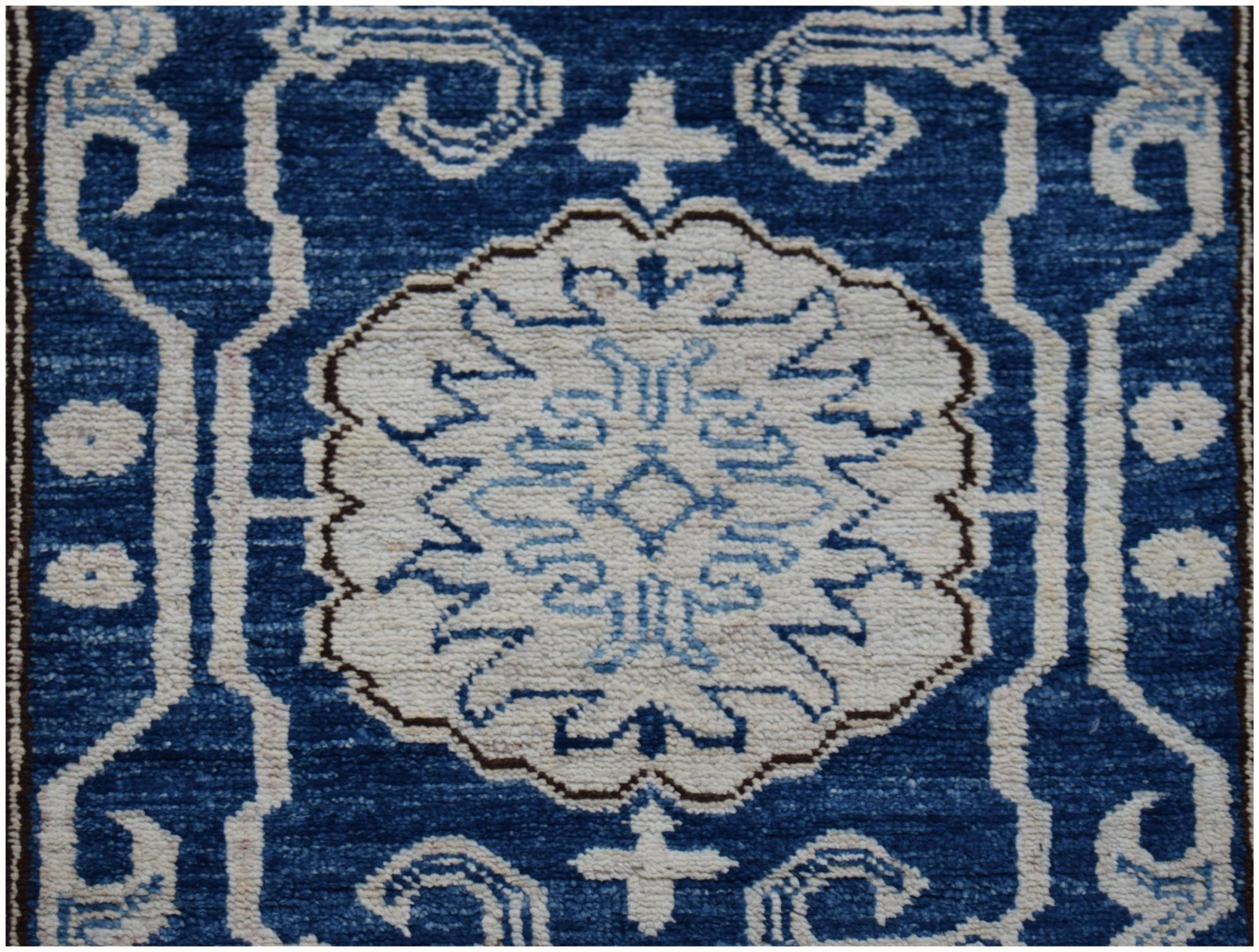 An Afghan Super Kazakh runner rug featuring a central white medallion on a deep blue background.