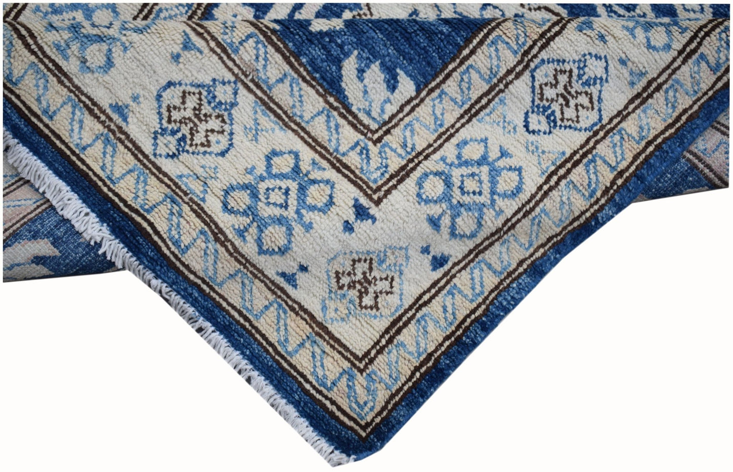 A corner view of a handmade Afghan Super Kazakh runner featuring blue and brown geometric patterns.