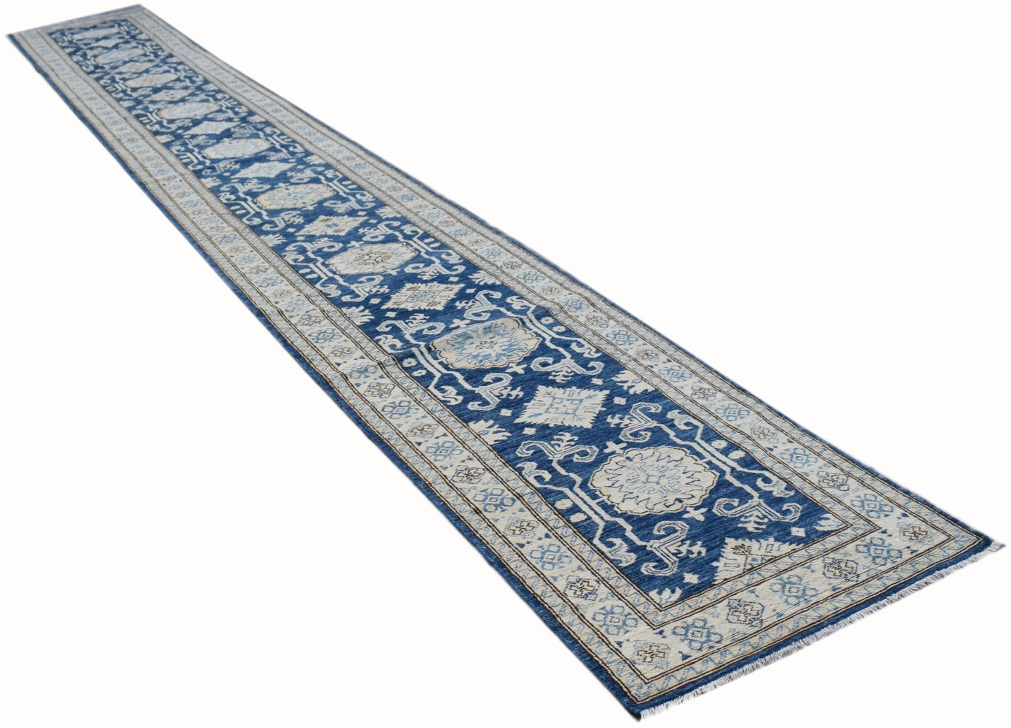 A long, handmade Afghan Super Kazakh runner rug featuring a blue field with beige geometric motifs.