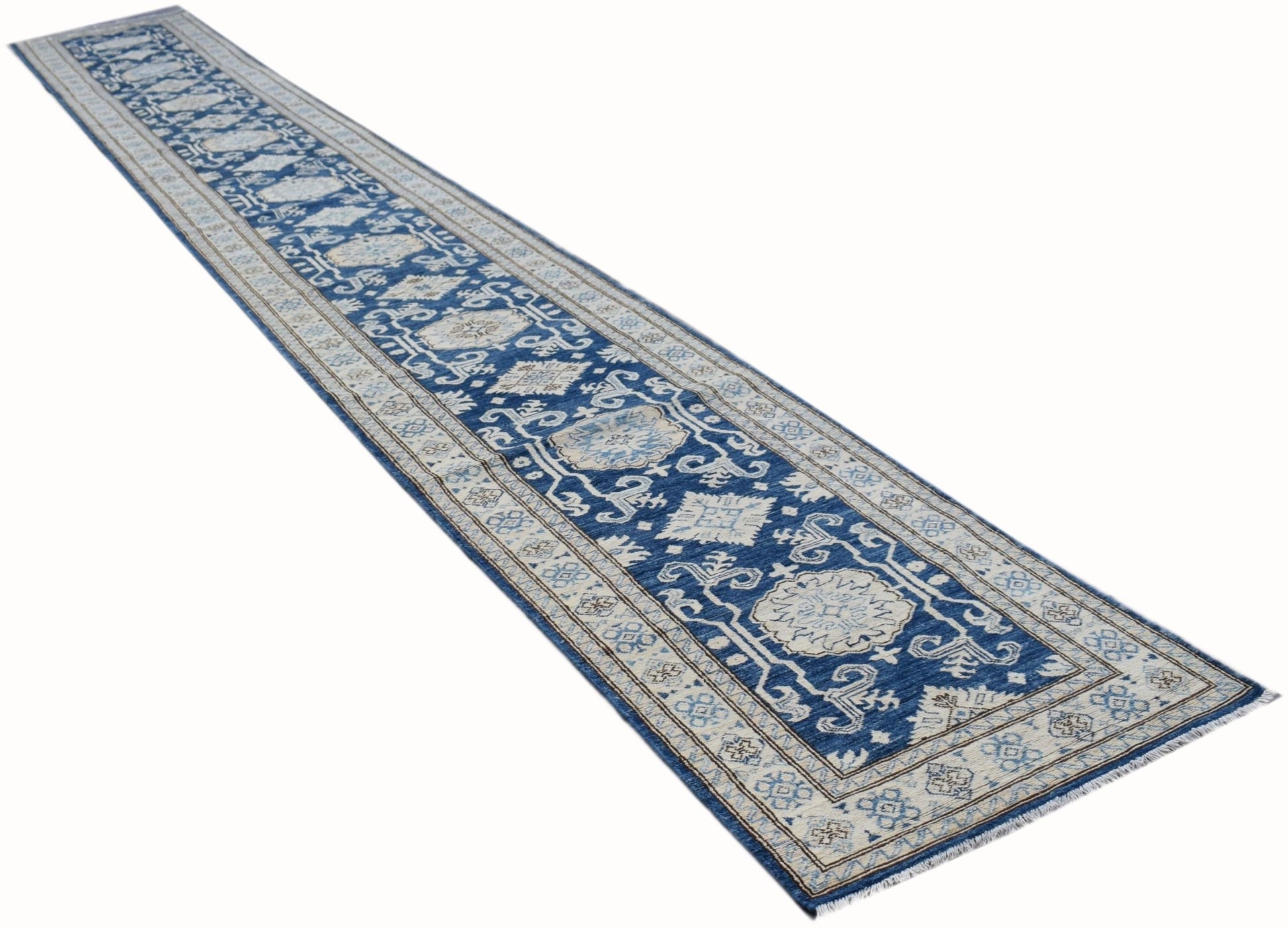 A long, handmade Afghan Super Kazakh runner rug featuring a blue field with beige geometric motifs.