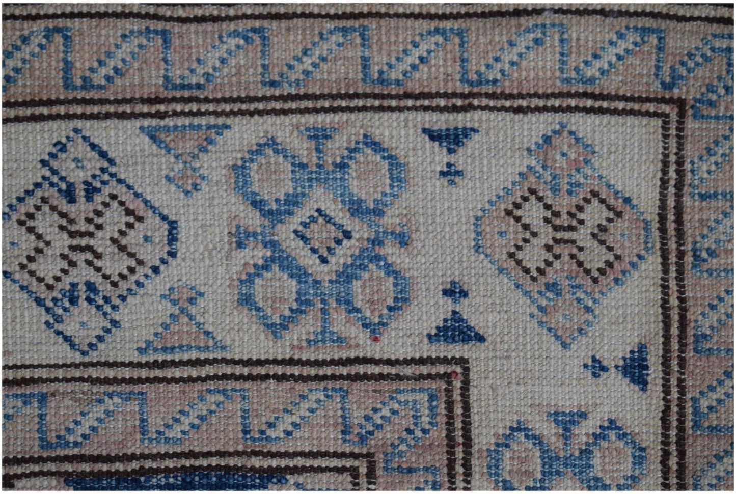 A handmade Afghan Super Kazakh runner featuring a geometric pattern in beige and blue wool.
