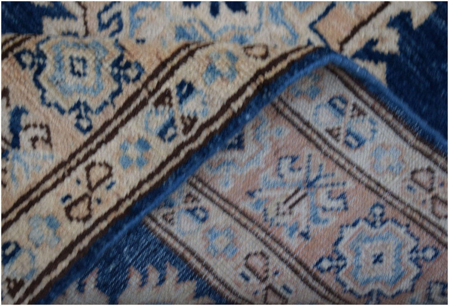 A folded Afghan Super Kazakh runner featuring a traditional geometric pattern in blue and beige.