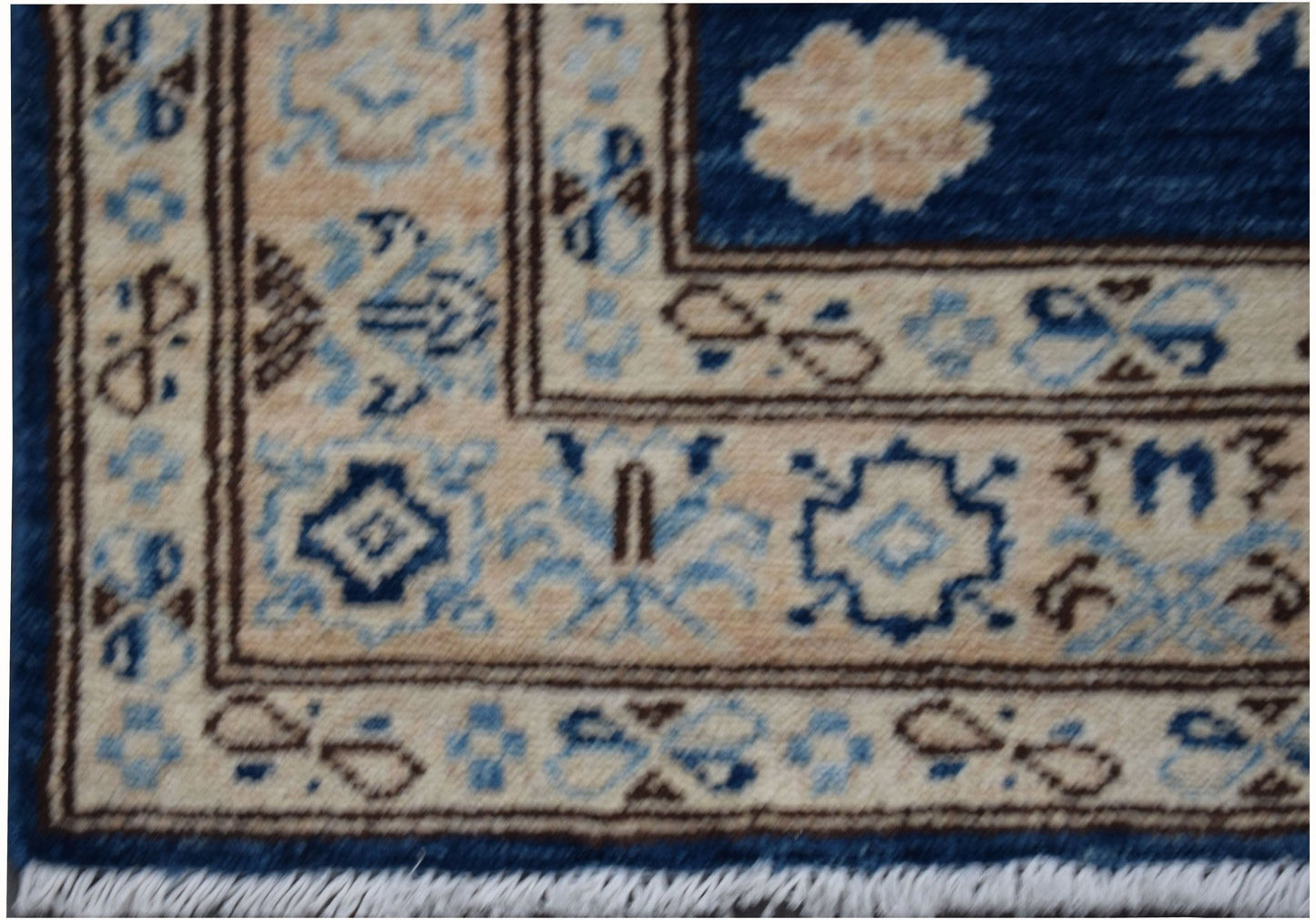A close-up of an Afghan Super Kazakh runner rug featuring geometric patterns in blue and beige.