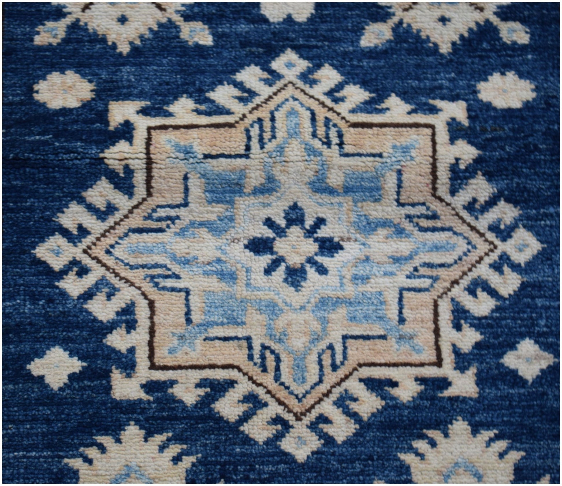 A handmade Afghan runner rug featuring a central geometric star motif in shades of blue and beige.