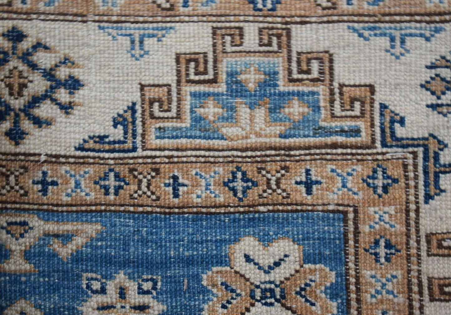 A close-up of a handmade Afghan Super Kazakh runner featuring traditional geometric motifs in blue and tan.
