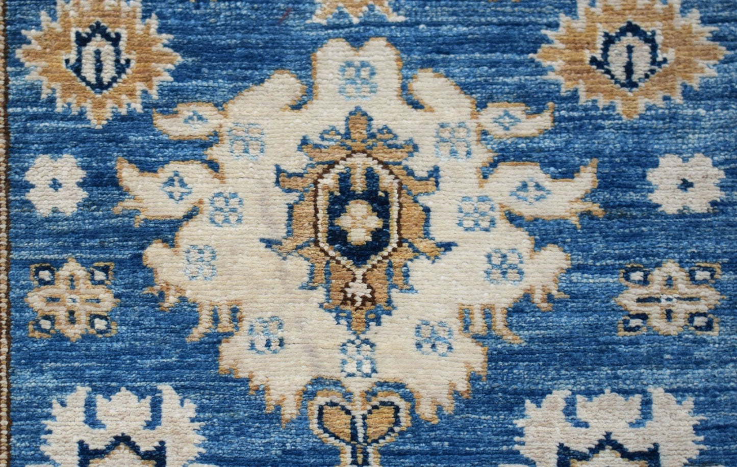 A handmade Afghan Super Kazakh runner featuring traditional cream and blue floral motifs.