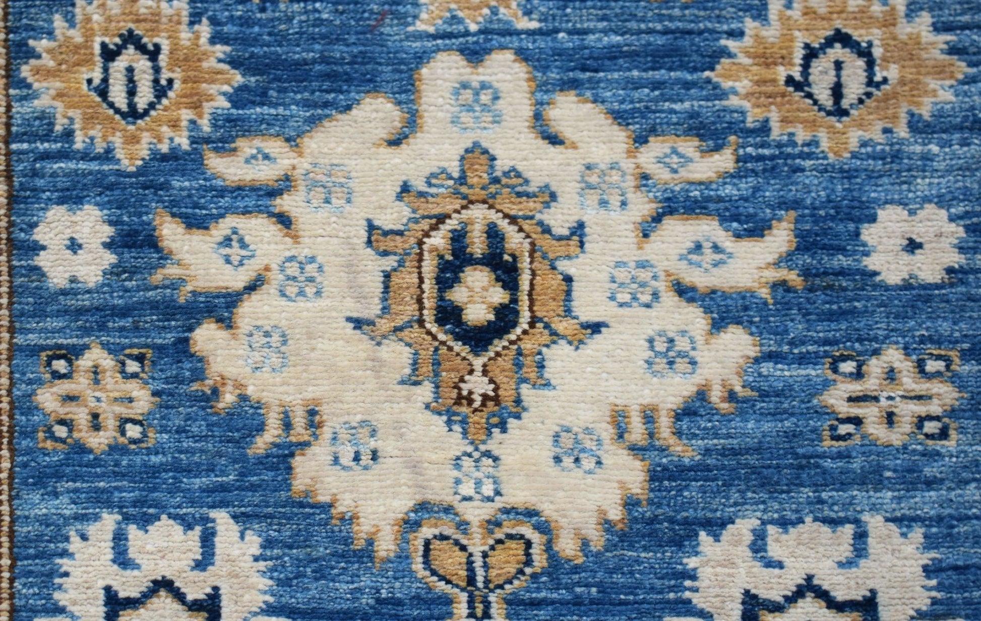 A handmade Afghan Super Kazakh runner featuring traditional cream and blue floral motifs.