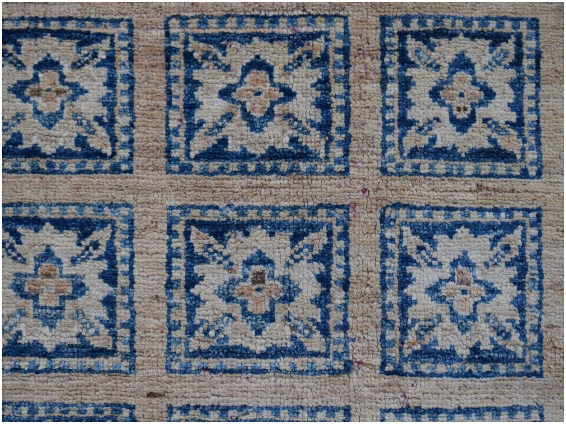 Handmade Afghan Chobi rug featuring a repeating blue and beige geometric floral pattern.