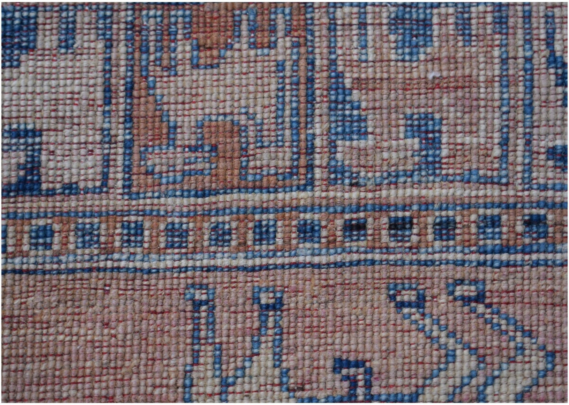 A close-up of a handmade Afghan Chobi rug featuring geometric patterns in blue, beige, and grey.