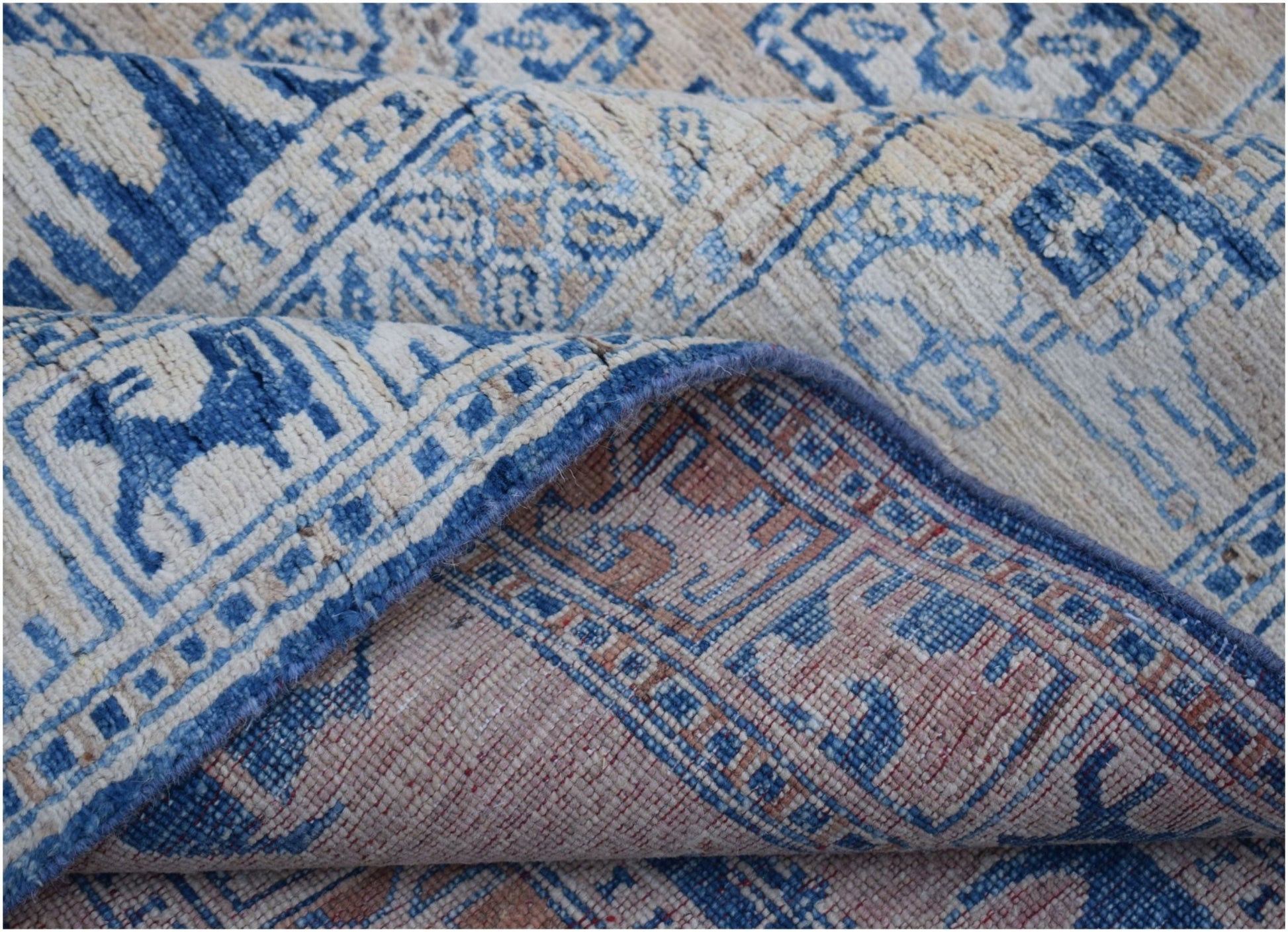 A handmade Afghan Chobi rug featuring a blue and beige geometric Pazyryk pattern.