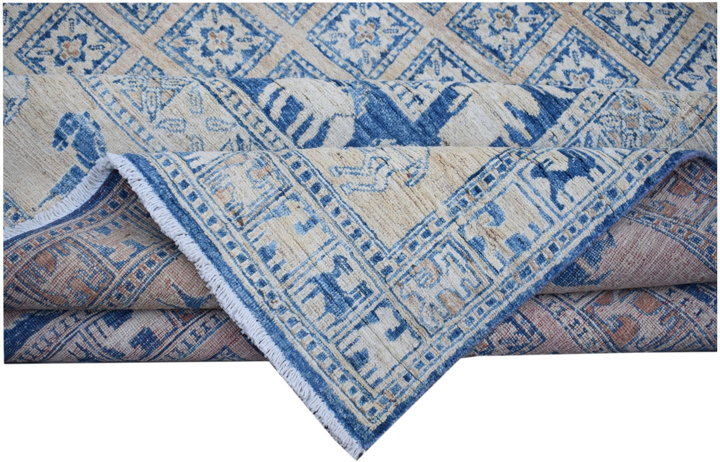 A folded Afghan Chobi rug featuring a blue and beige geometric Pazyryk pattern on wool.