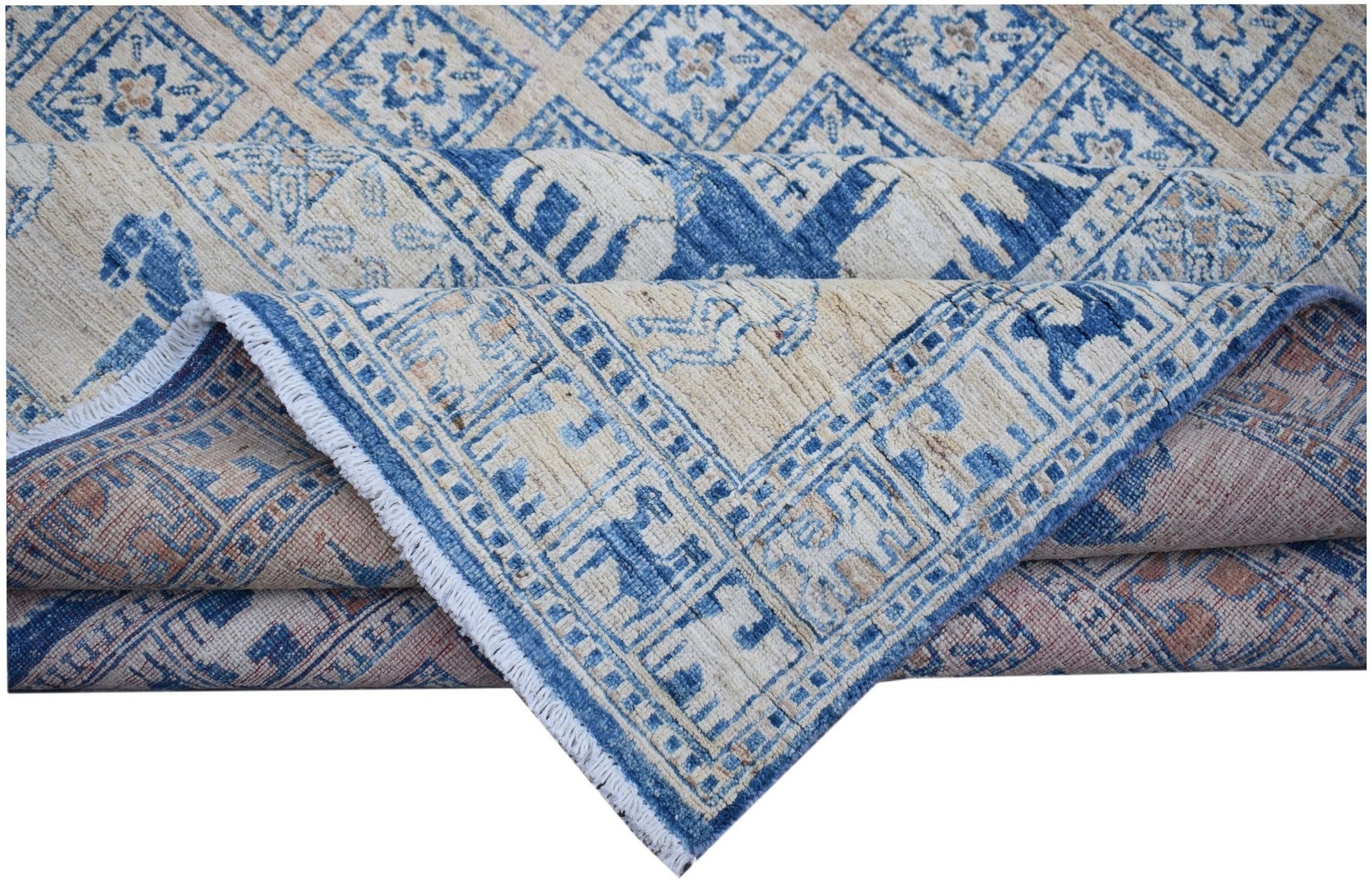 A folded Afghan Chobi rug featuring a blue and beige geometric Pazyryk pattern on wool.