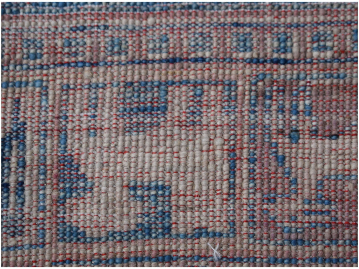 A close-up of a handmade Afghan Chobi rug featuring a geometric pattern in beige, blue, and red.