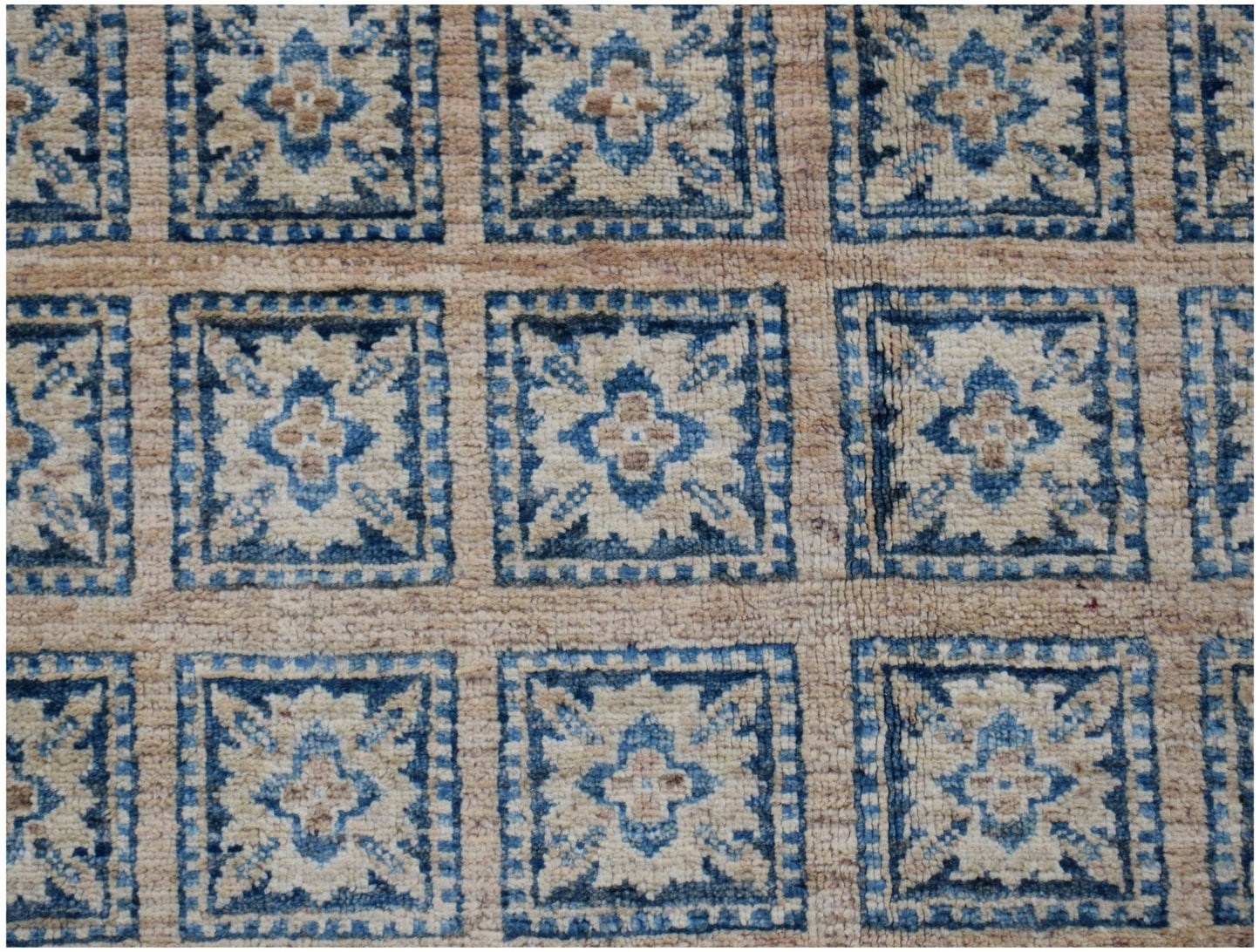 Handmade Afghan Chobi rug featuring a repeating grid of blue and beige floral geometric motifs.