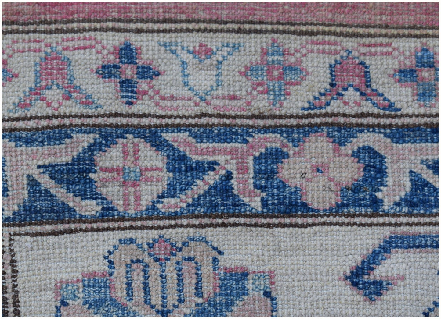 A close-up of an Afghan Super Kazakh rug featuring intricate blue and pink floral geometric patterns.