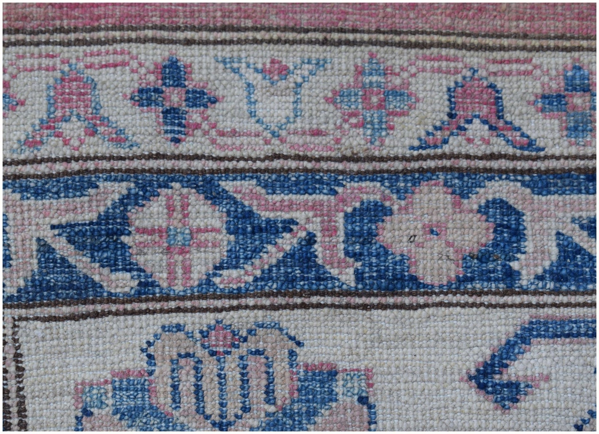 A close-up of an Afghan Super Kazakh rug featuring intricate blue and pink floral geometric patterns.