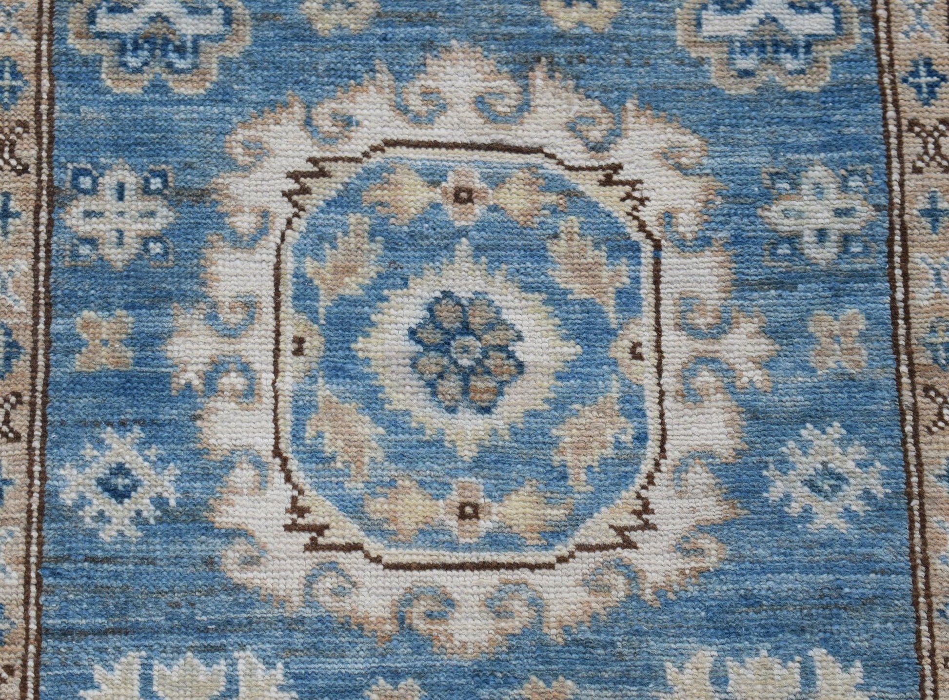 An Afghan Super Kazakh runner rug featuring a blue field with traditional cream floral motifs.