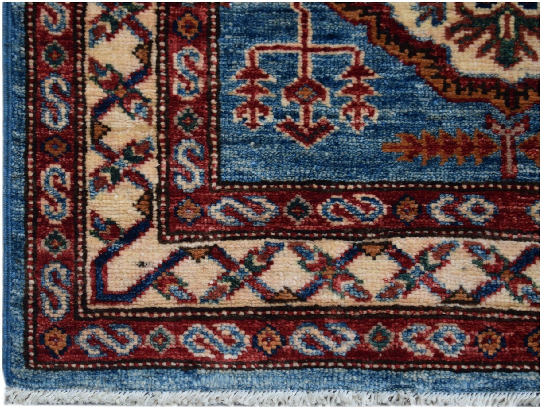 A close-up of an Afghan Super Kazakh runner featuring traditional geometric patterns in blue and red.