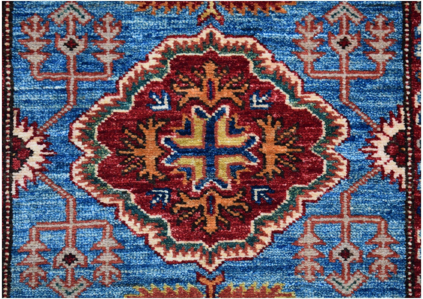An Afghan Super Kazakh runner featuring a central red medallion with geometric motifs on a blue field.