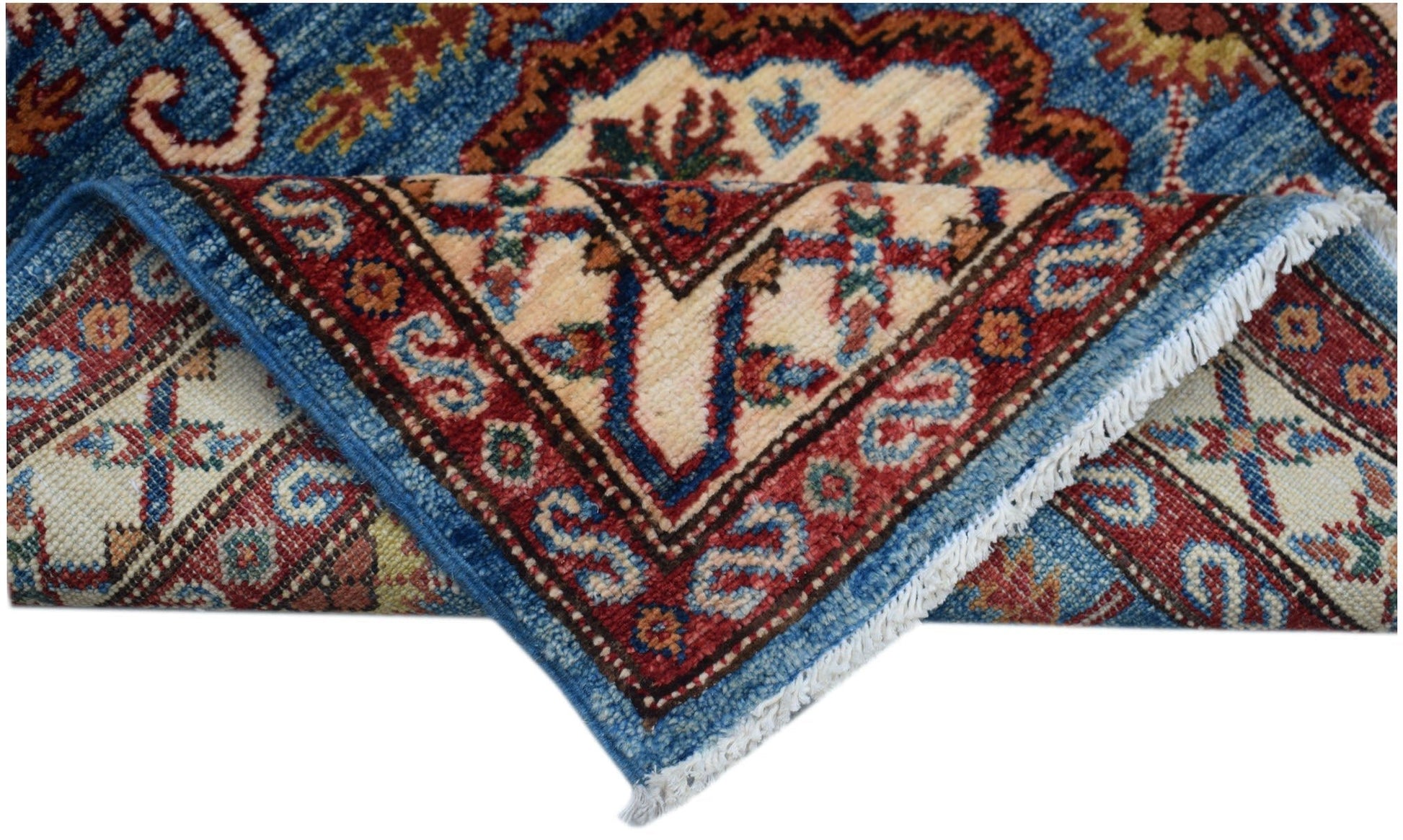 A folded Afghan Super Kazakh runner featuring traditional geometric motifs in blue and red wool.
