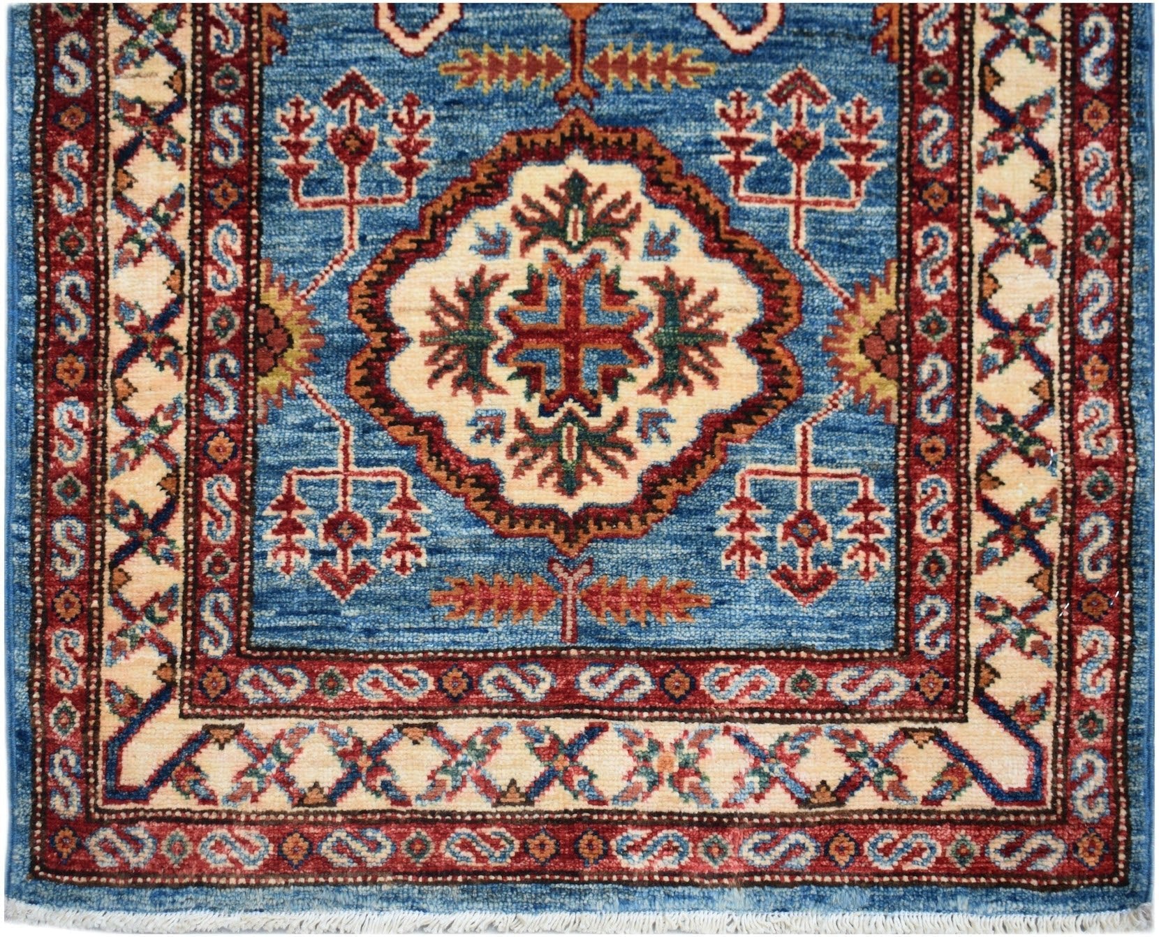 Handmade Afghan Super Kazakh runner featuring a central medallion on a blue field with red borders.