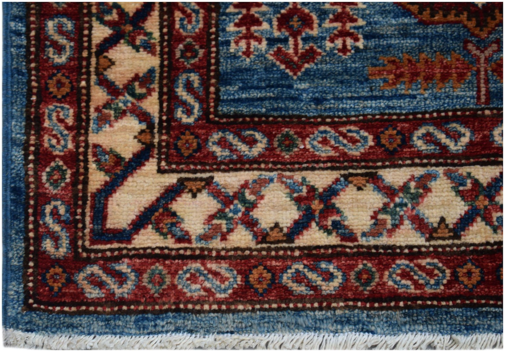 A close-up of an Afghan Super Kazakh runner featuring traditional geometric motifs in red and blue.