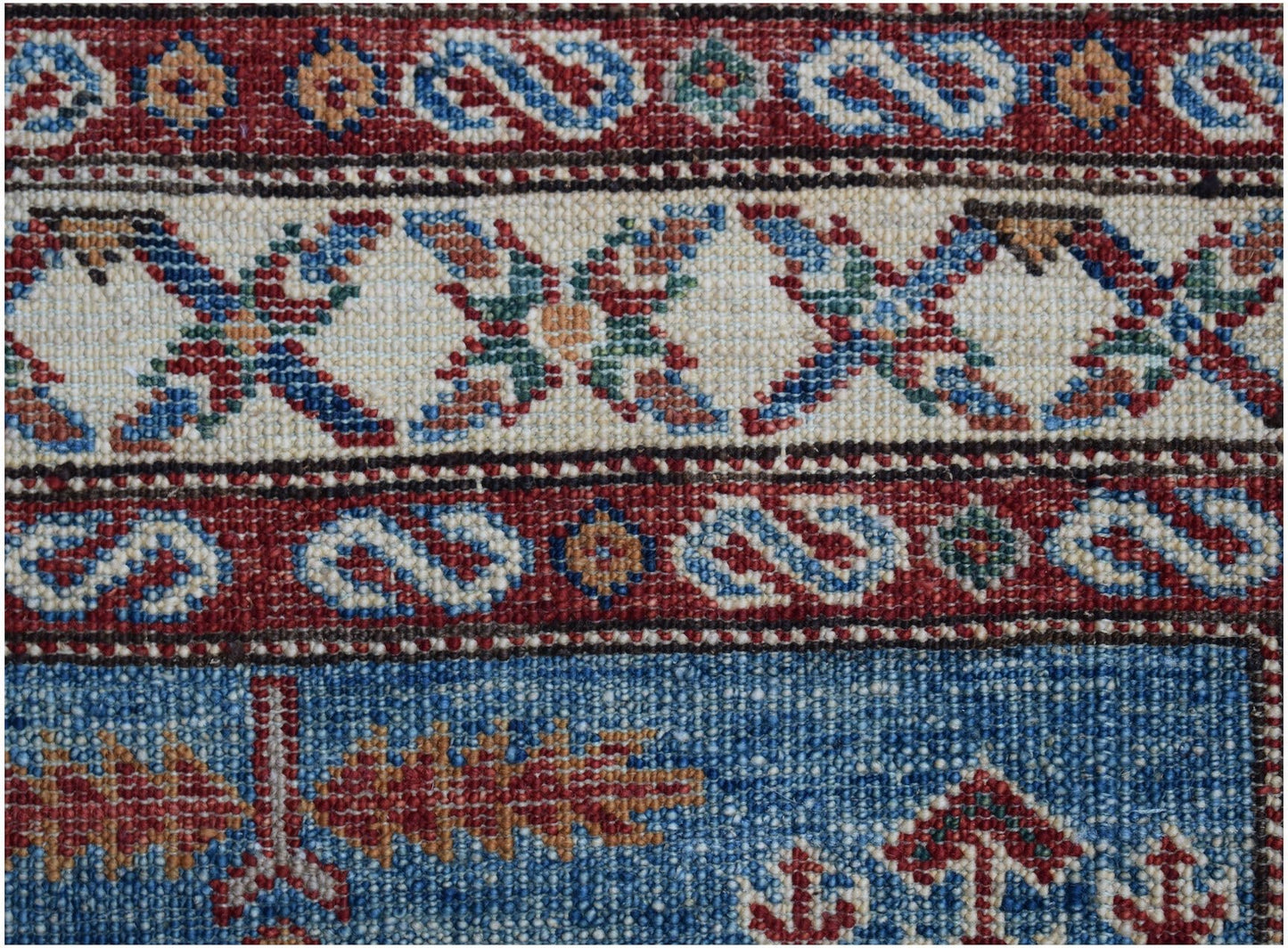 A close-up of an Afghan Super Kazakh runner featuring traditional geometric patterns in wool.