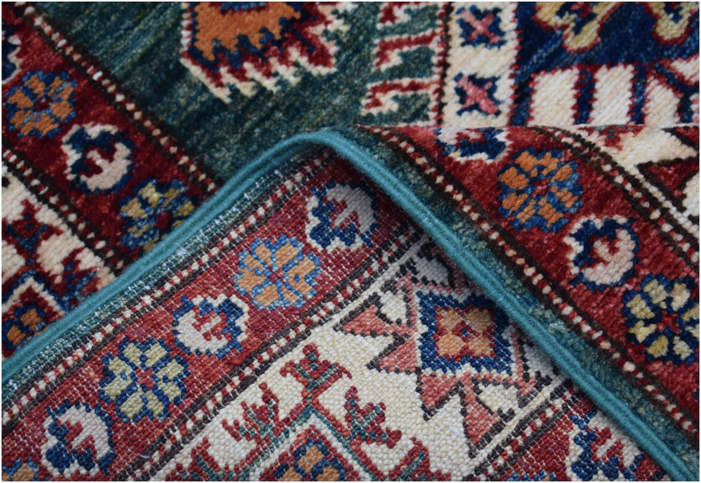 A folded Afghan Super Kazakh runner featuring traditional geometric motifs in red, blue, and cream.