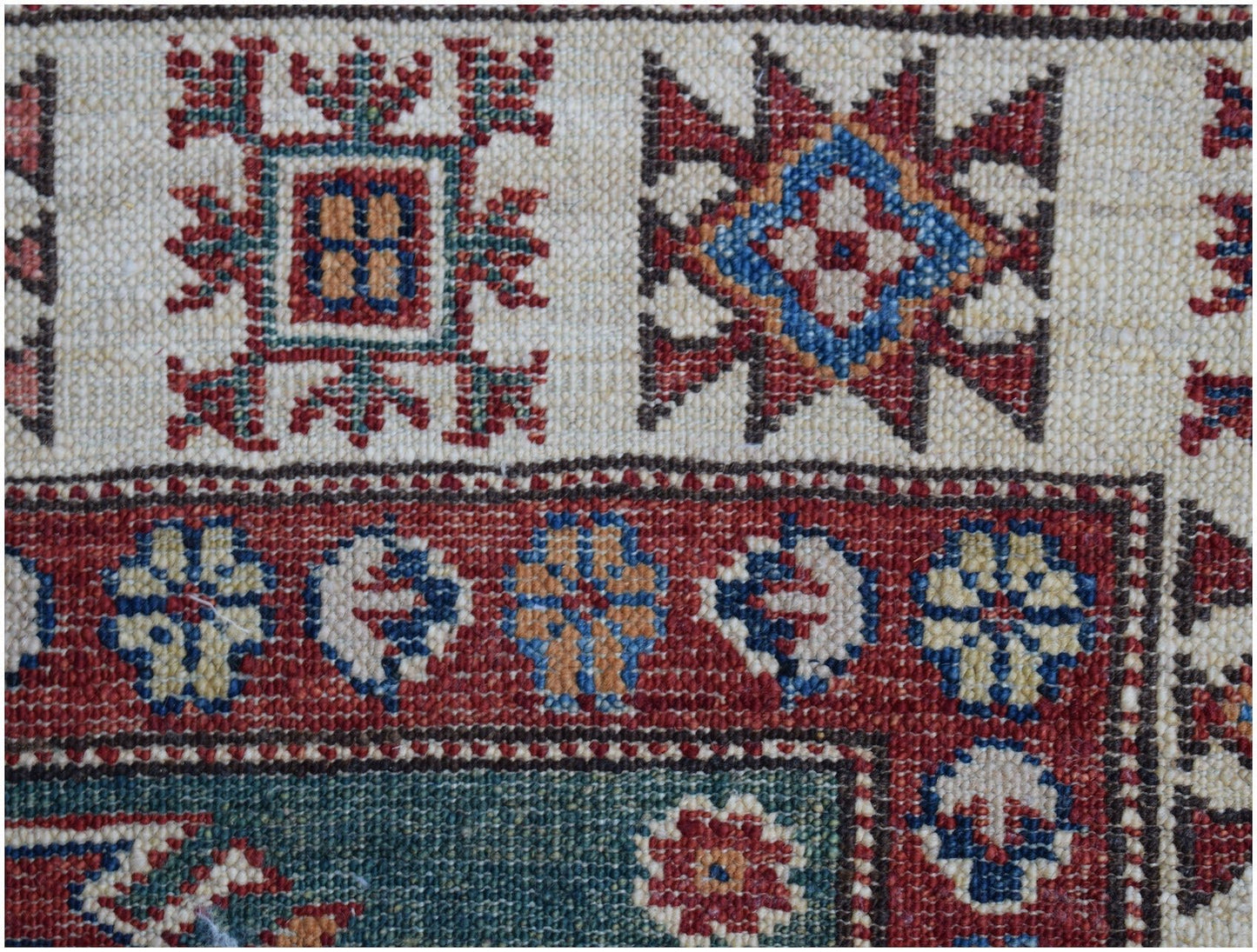 A close-up of an Afghan Super Kazakh runner featuring traditional geometric motifs in wool.