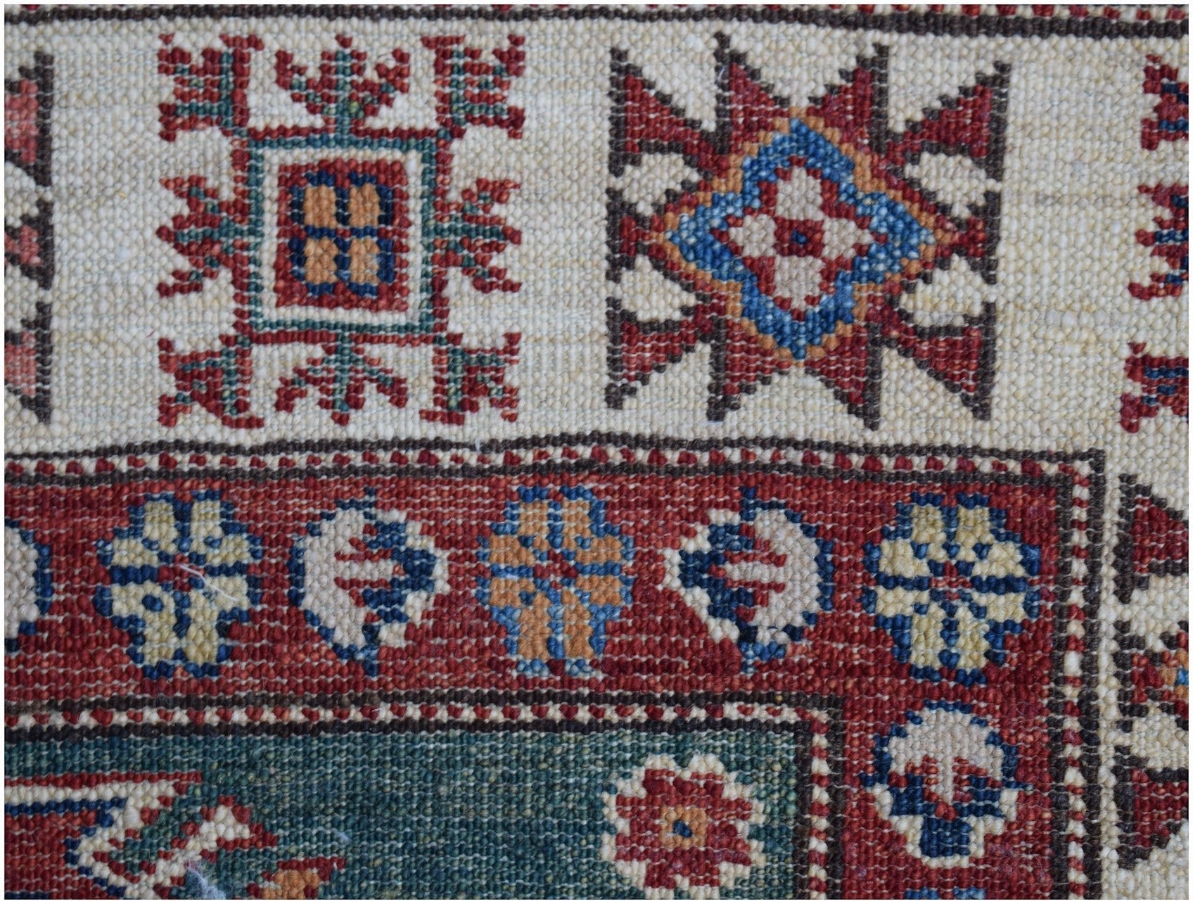 A close-up of an Afghan Super Kazakh runner featuring traditional geometric motifs in wool.