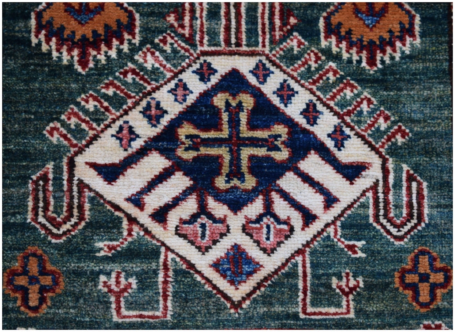 A handmade Afghan Super Kazakh runner featuring a central cross motif on a deep blue background.