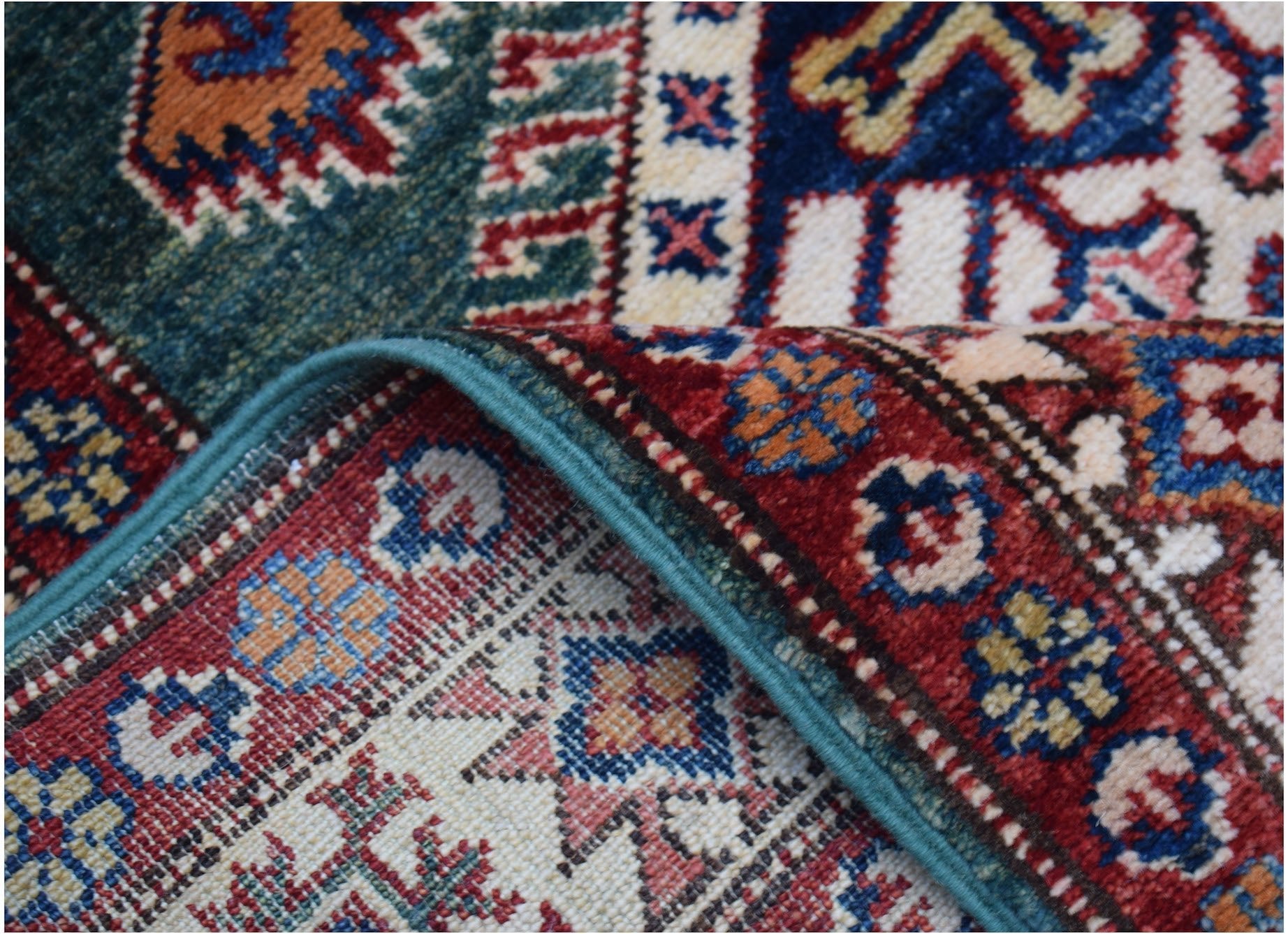 A folded Afghan Super Kazakh runner featuring traditional geometric motifs in red, blue, and cream.